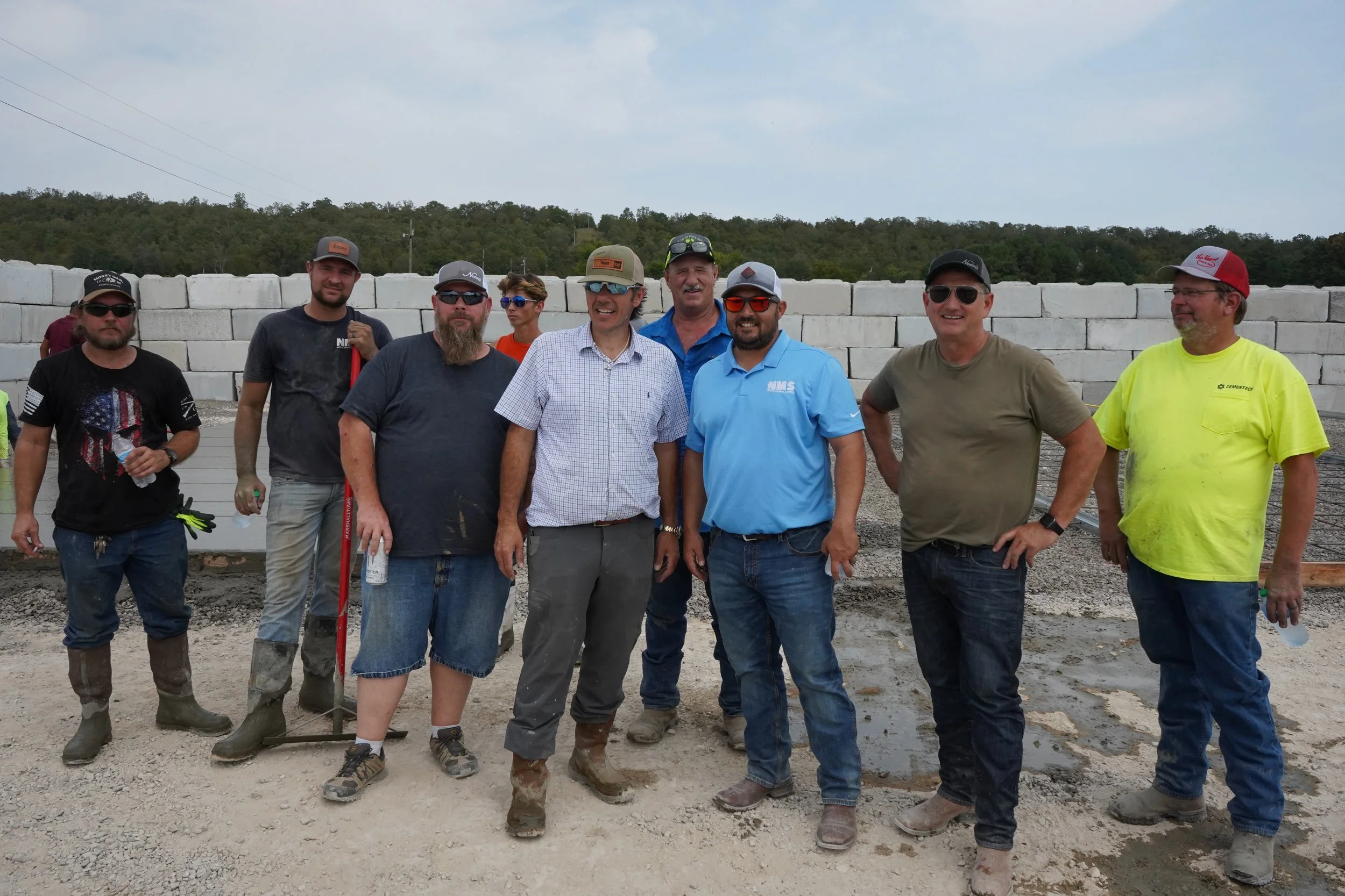 A team of professional concrete contractors and construction workers smiling together on-site after completing a foundation project.