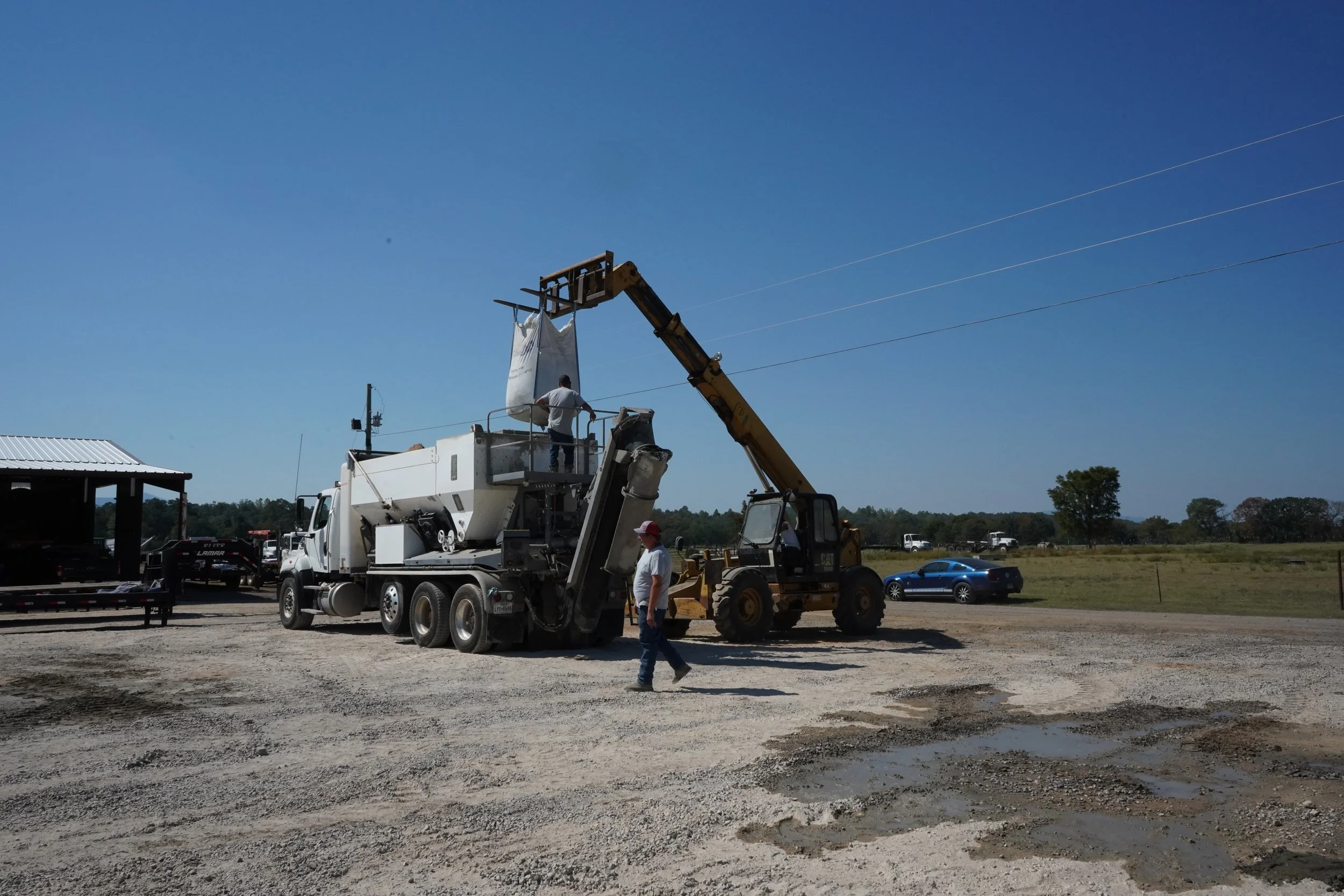 Sirron field technicians safely managing bulk material distribution into a supply truck under a clear sky.