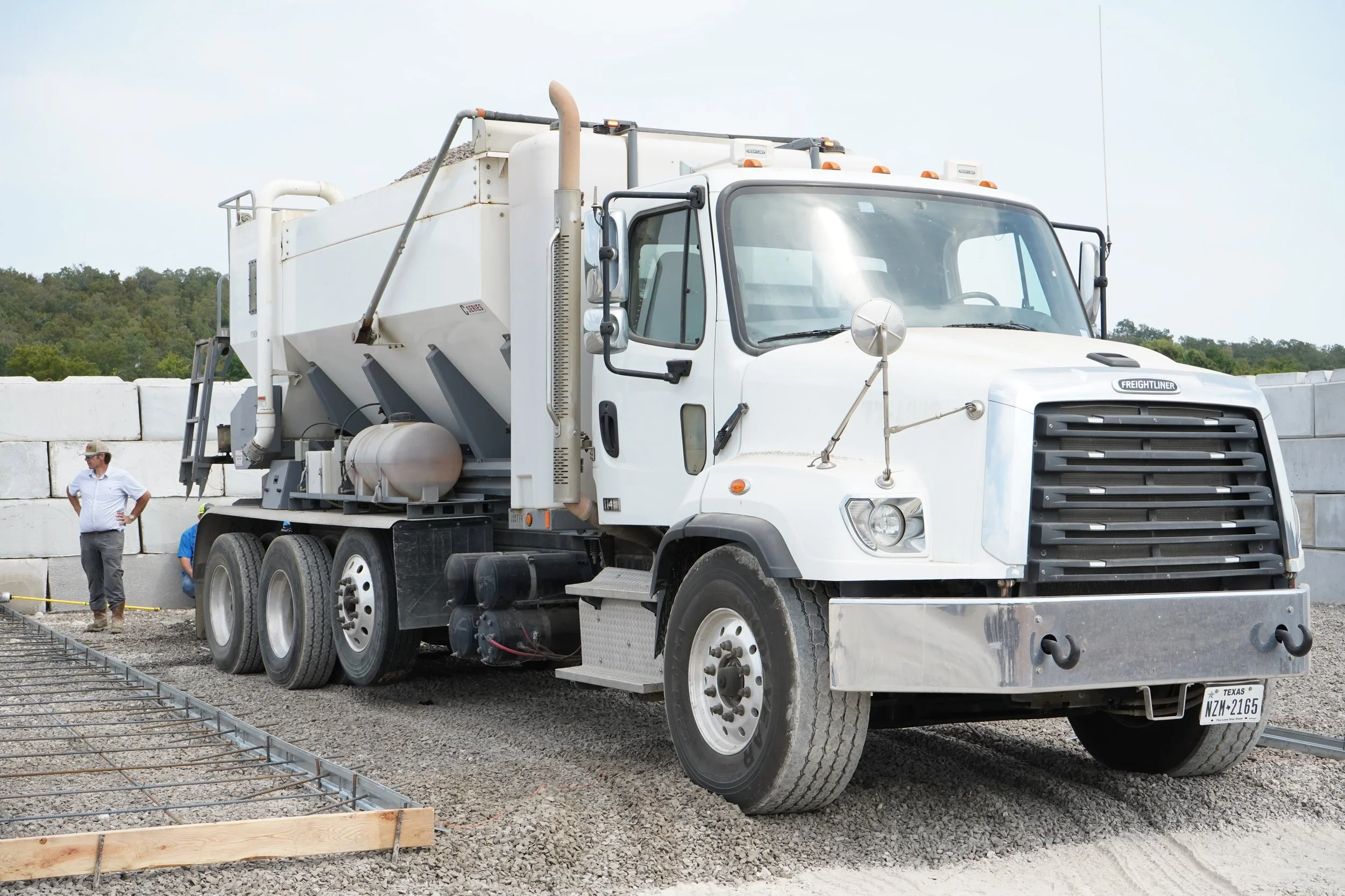 Sirron company Freightliner volumetric concrete mixer truck staged next to a steel rebar grid and wooden formwork for a foundation pour.