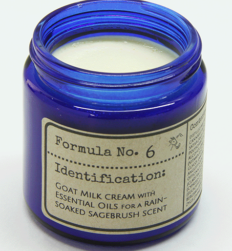 Open blue glass jar of Formula No. 6 goat milk cream with essential oils in a rain soaked sagebrush scent showing the cream inside