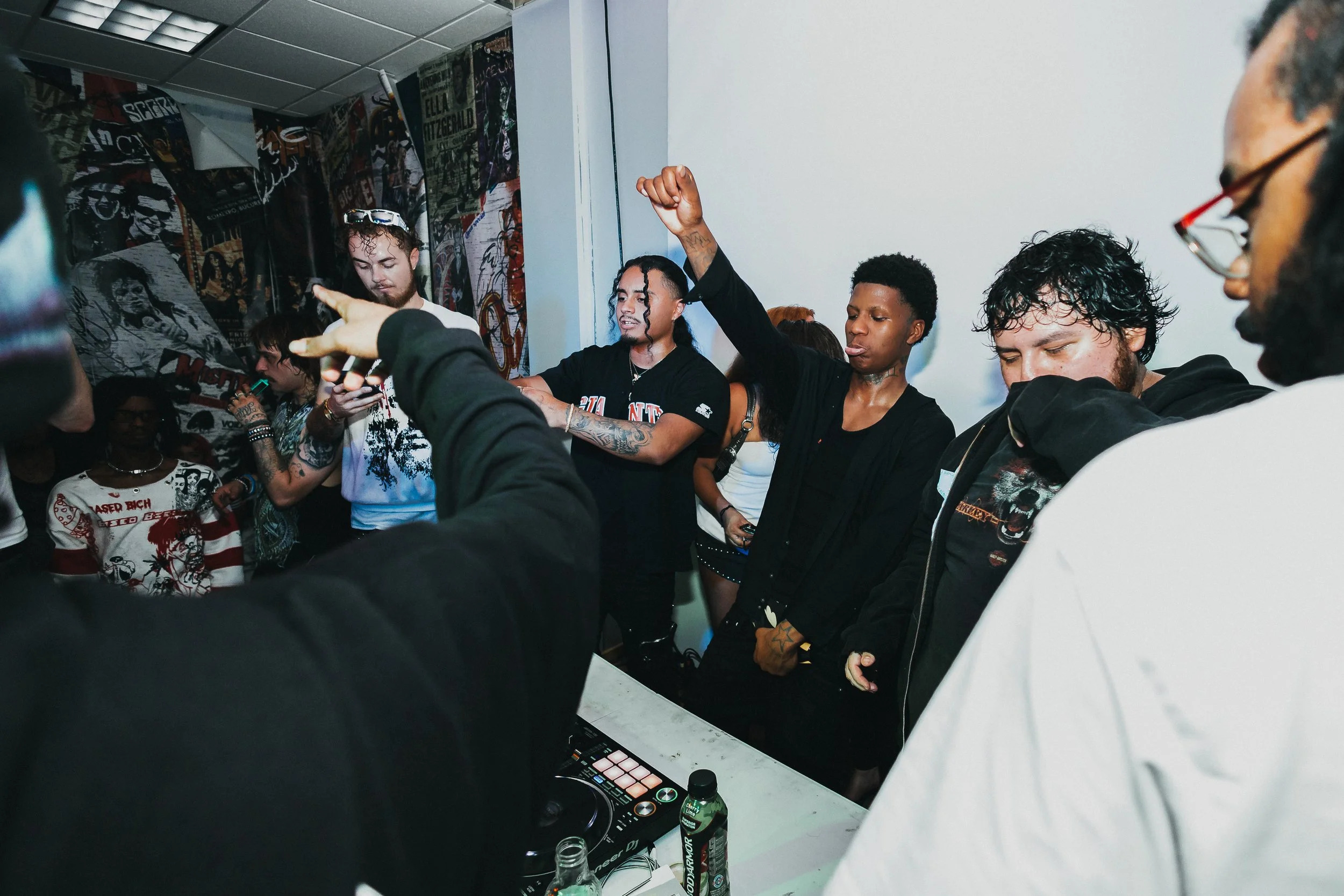 A group of young people dancing and enjoying music at a party or club with graffiti-style artwork on the wall.