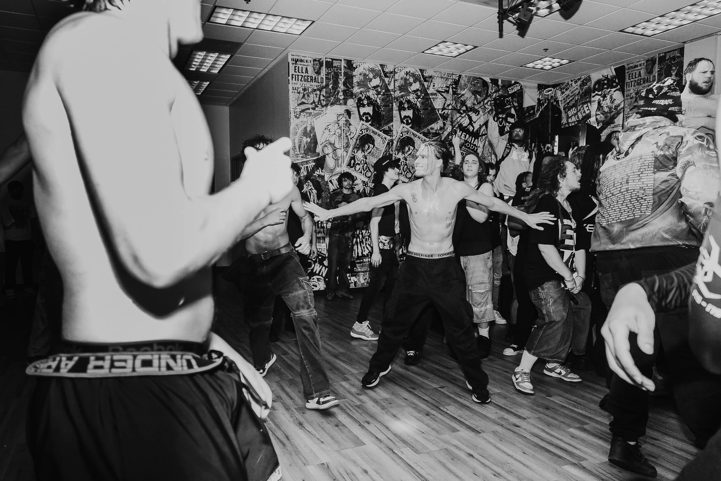 People dancing and enjoying music in a crowded indoor space with graffiti-style artwork on the walls.