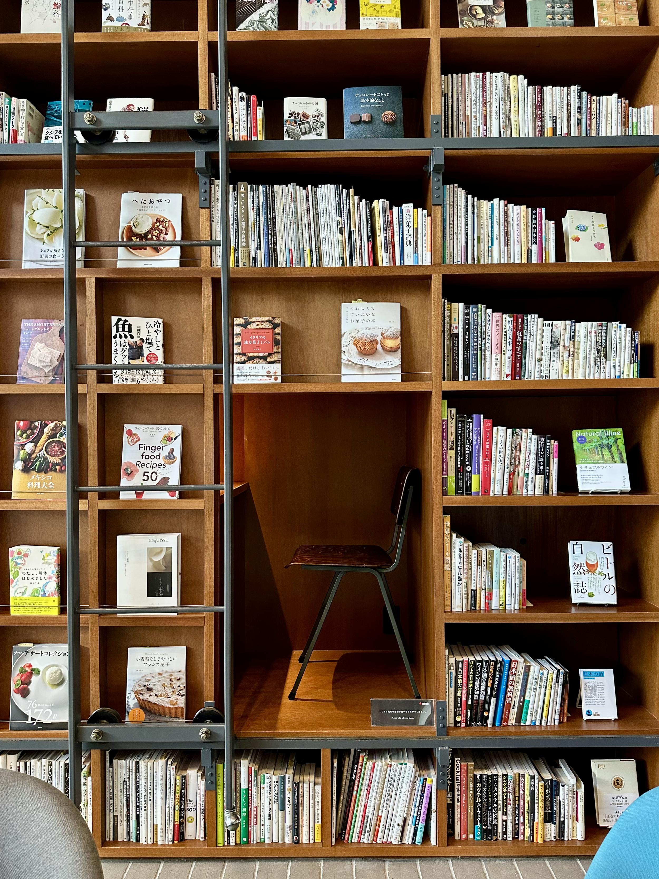 books on a series of boxed out shelves with one box large enough to enter that has a chair and a light with enough room to sit inside the larger bookshelf