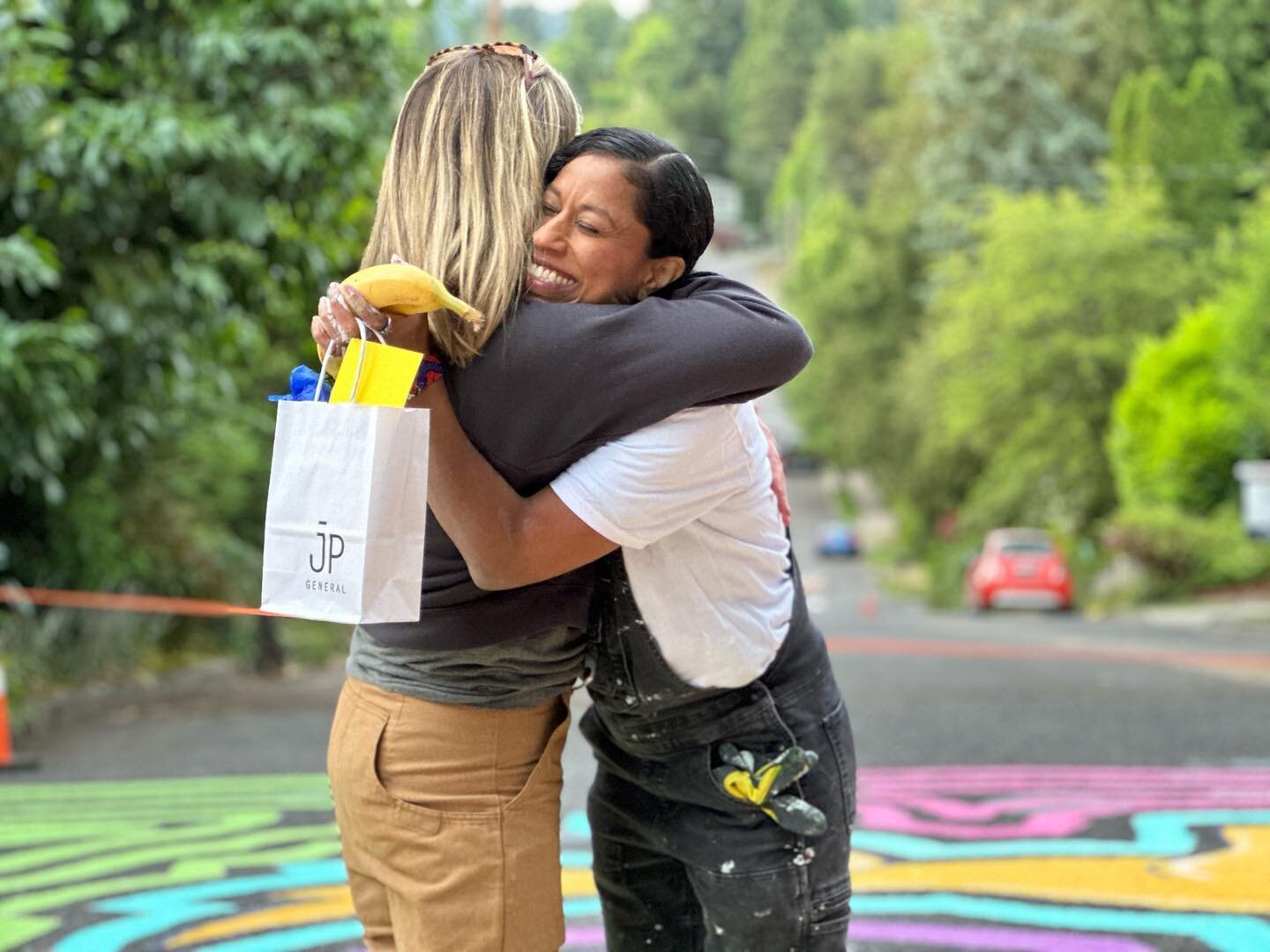 Our mural artist @curlieturtle and community events co-chair @cesannes hug as the day comes to an end.  Thank you again Amaranta for brining your art to our community. 

And thank you @jpgeneralshop for your continued support.