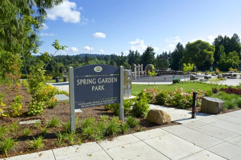 Spring Garden Park sign, with plants and play structure in foreground.