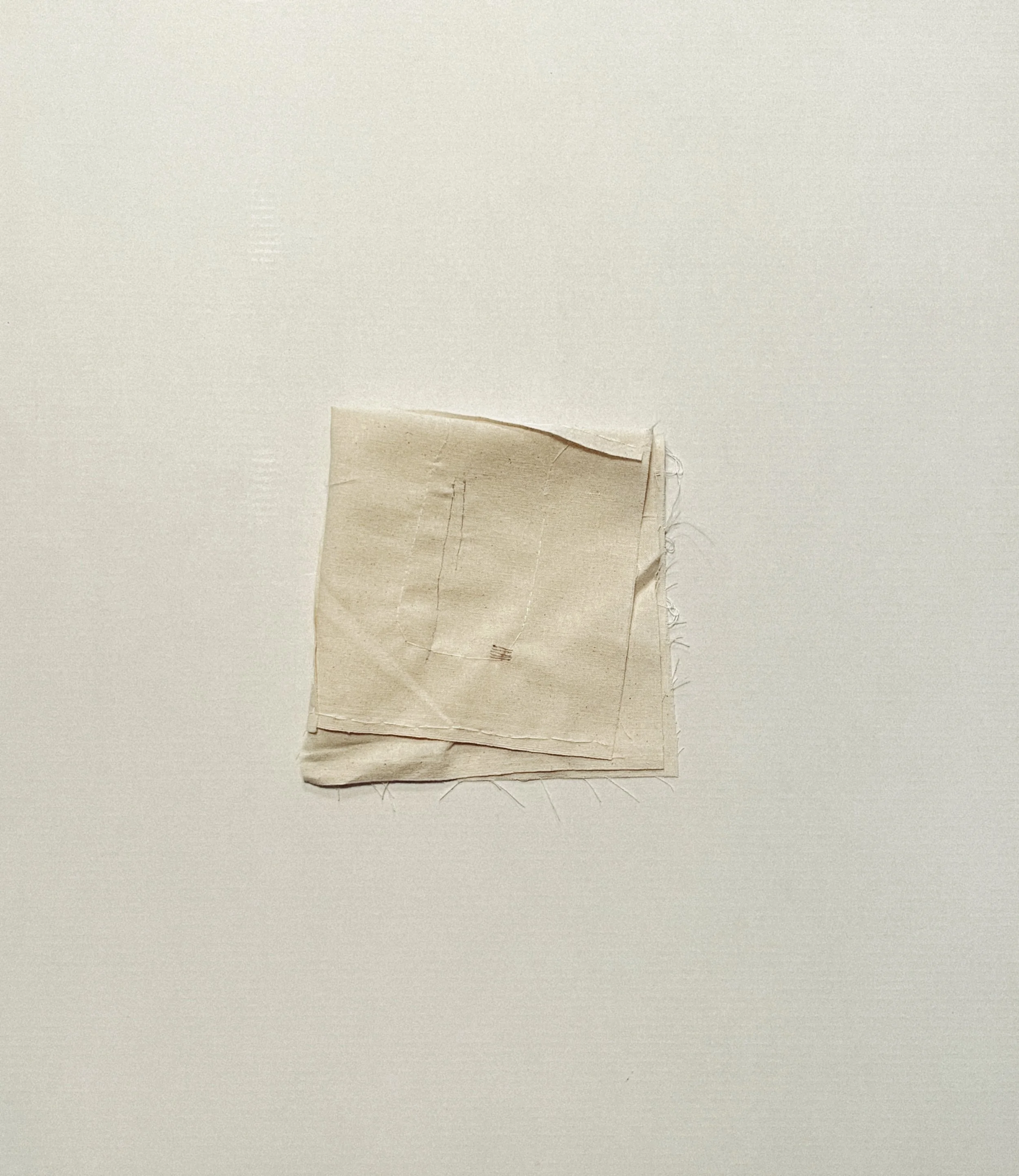 Pale hand-stitched cloth folded into a small layered form.