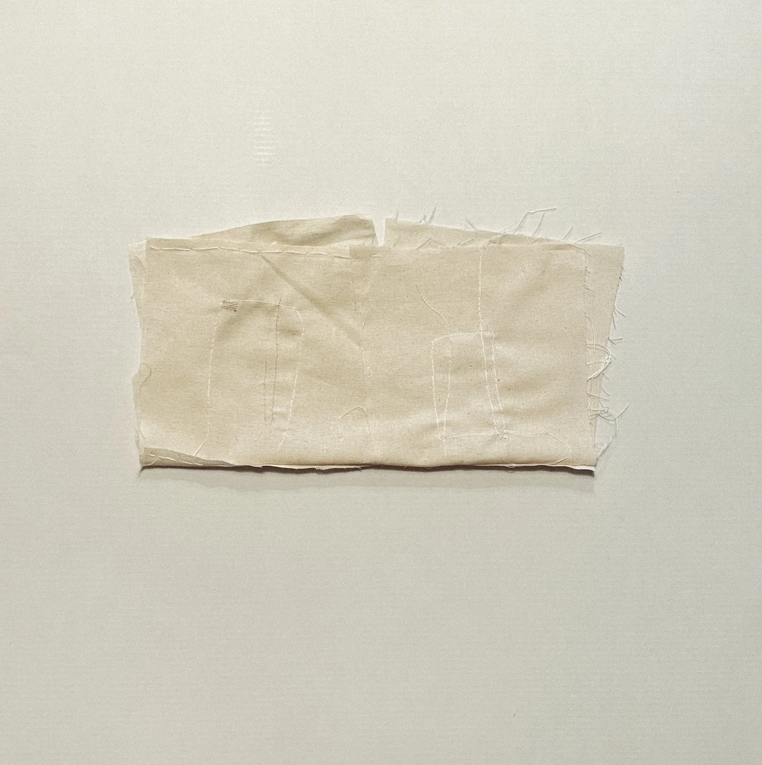 Off-white textile piece opened to reveal stitched inner folds and loose threads.