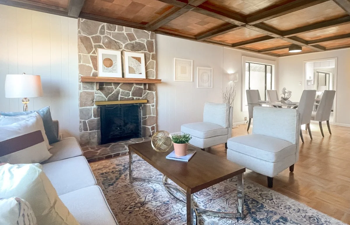 Cozy living room with stone fireplace, wood coffered ceiling and wood floors.