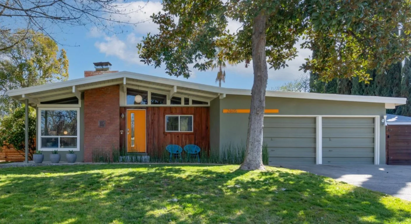 Mid Century Home with front gable roof, brick fireplace, 2 car garage and orange front door.