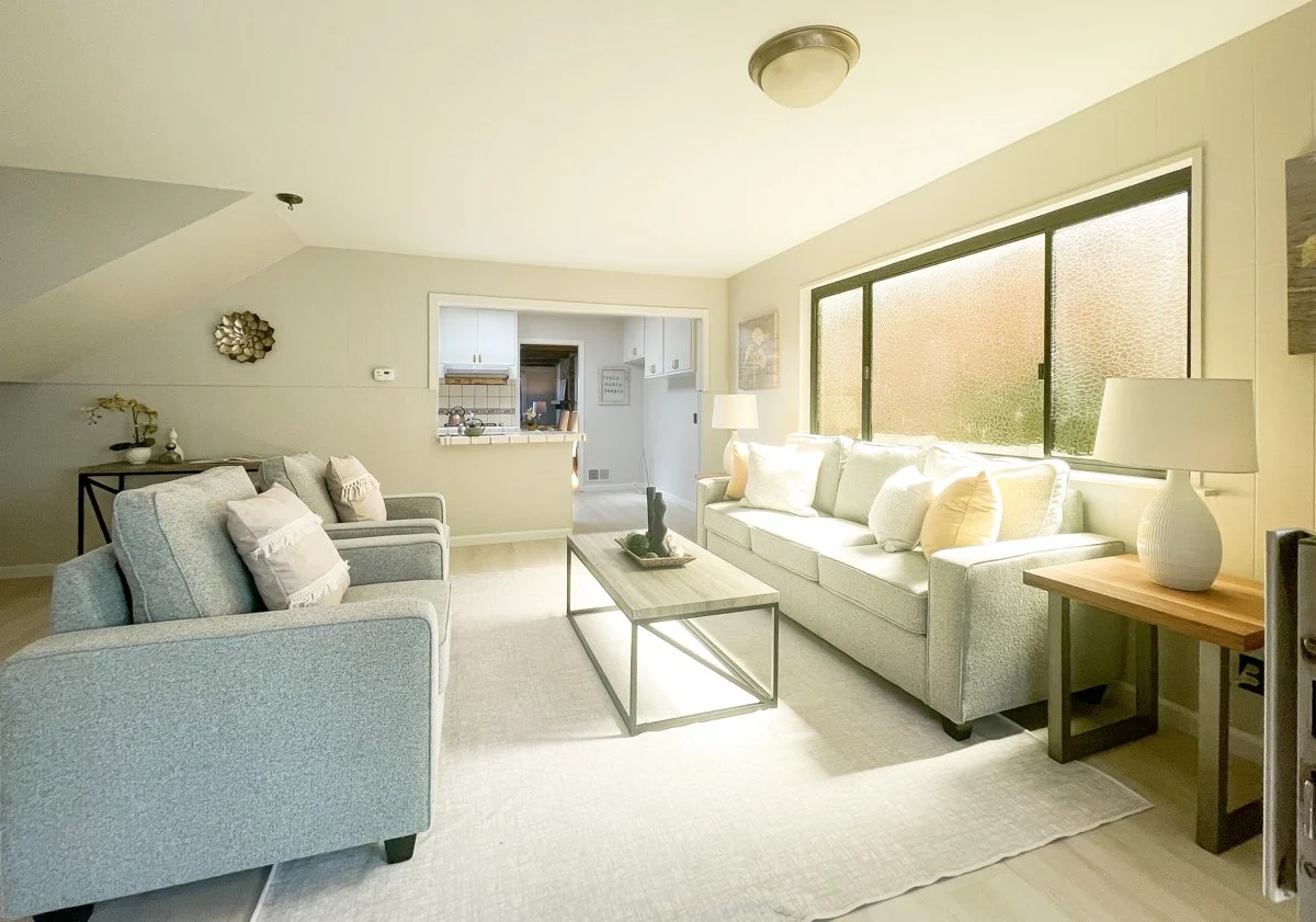 Family room brughtly lit with kitchen in background.