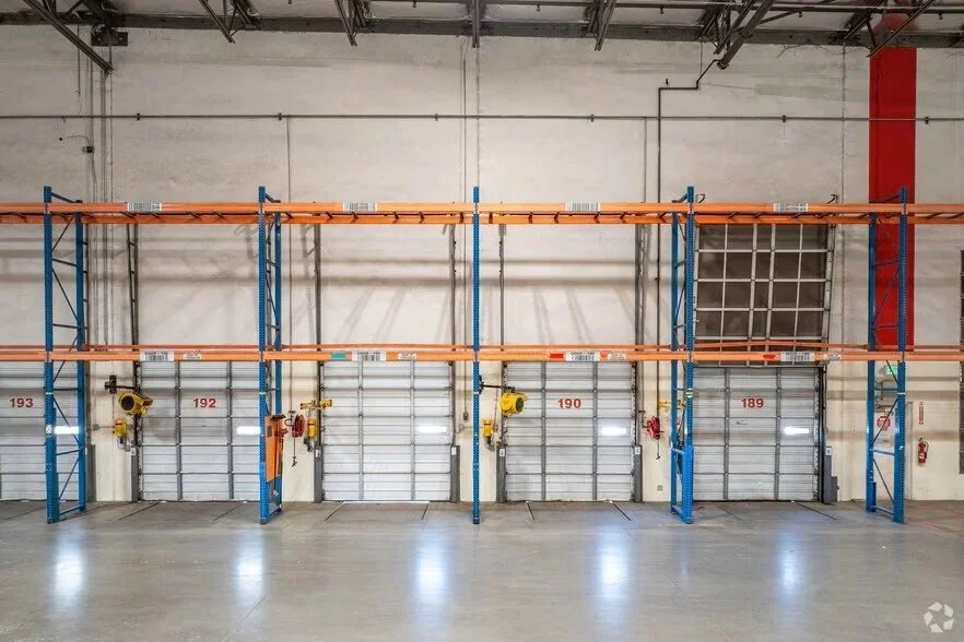 Empty warehouse with metal shelving units storing wooden pallets.