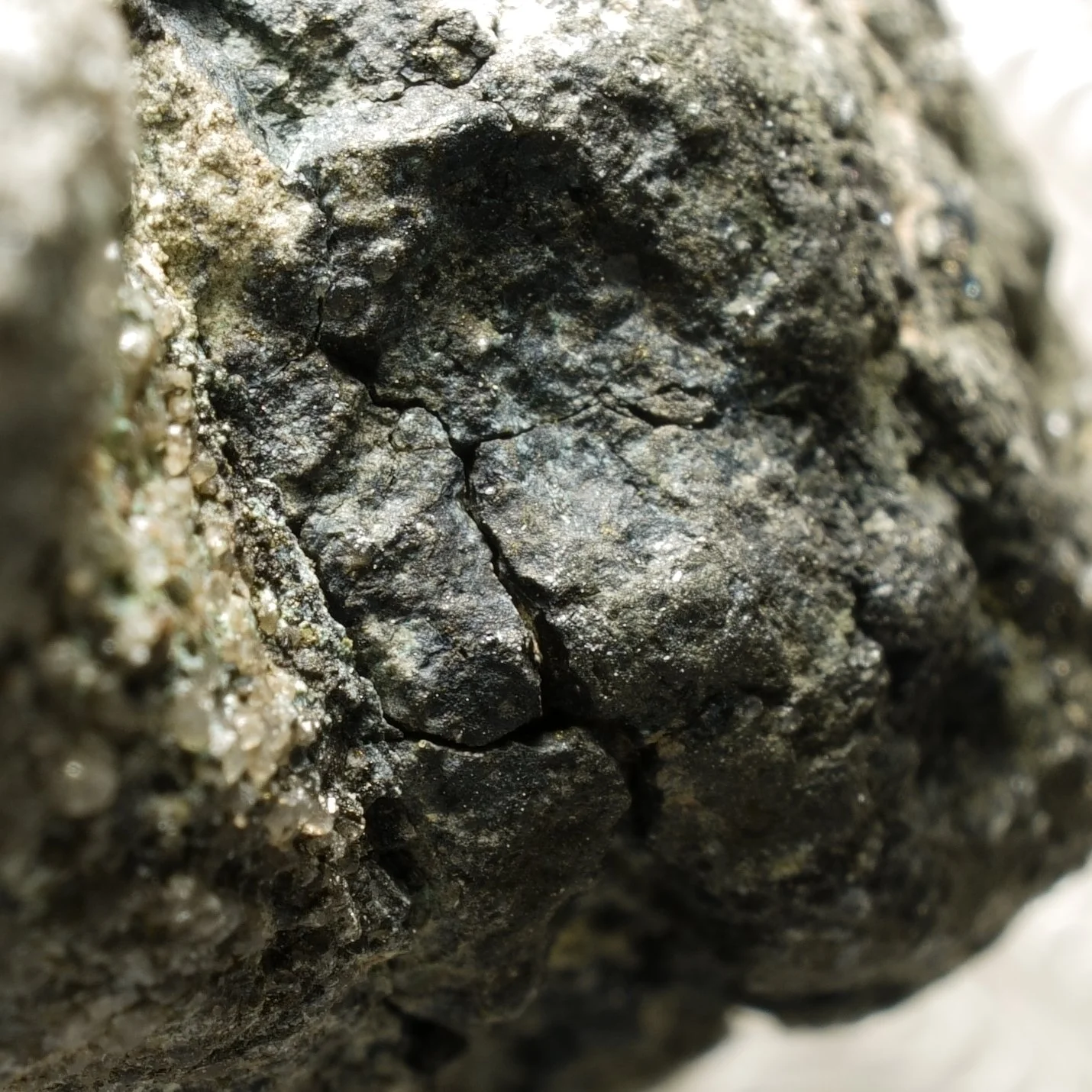 Uraninite uranium ore specimen in quartz matrix with dark primary mineralization and moderate green alteration