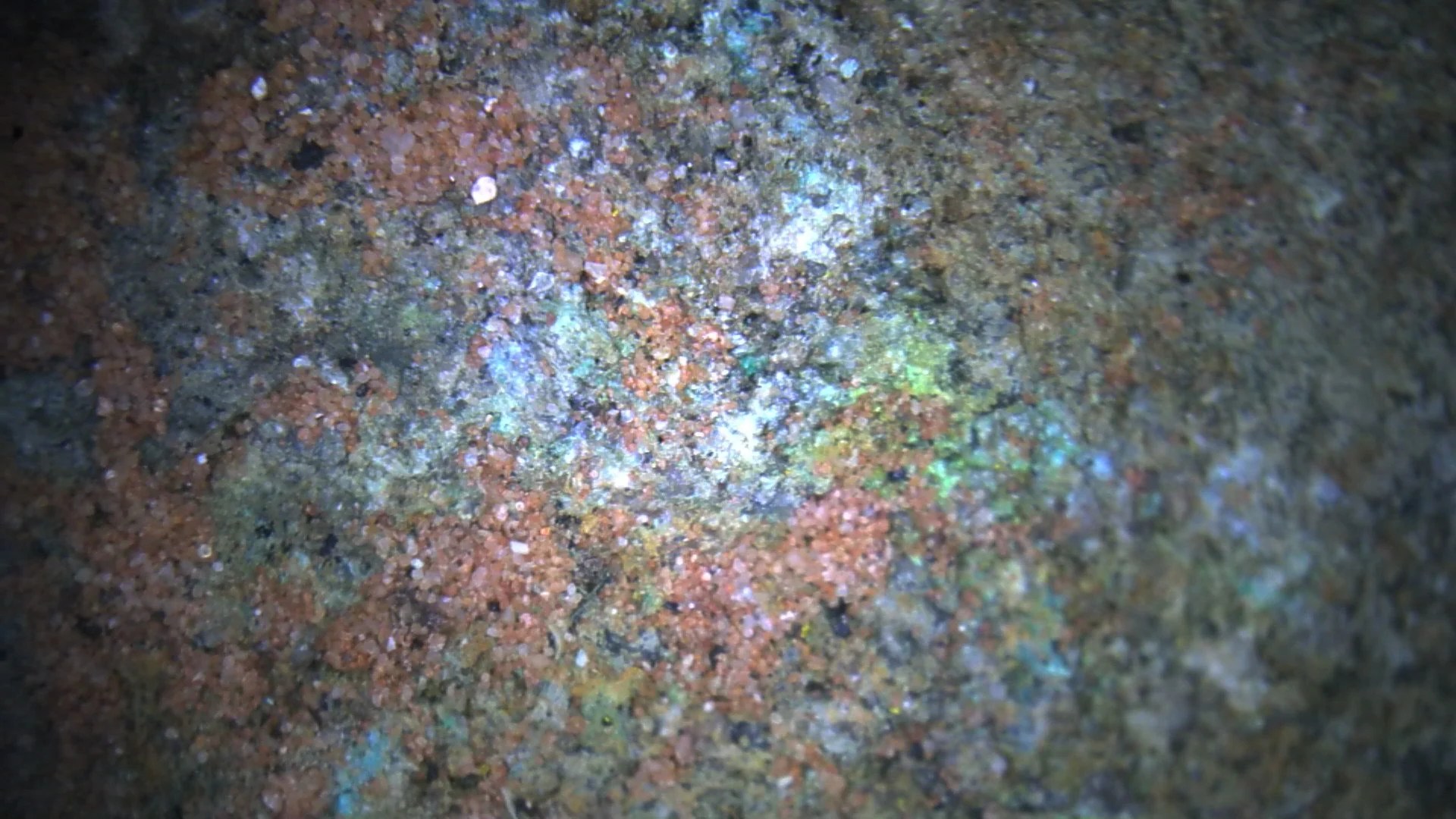 Magnified view of Hideout Mine uranium ore showing iron stained quartz and feldspathic sandstone grains with uranium mineralization