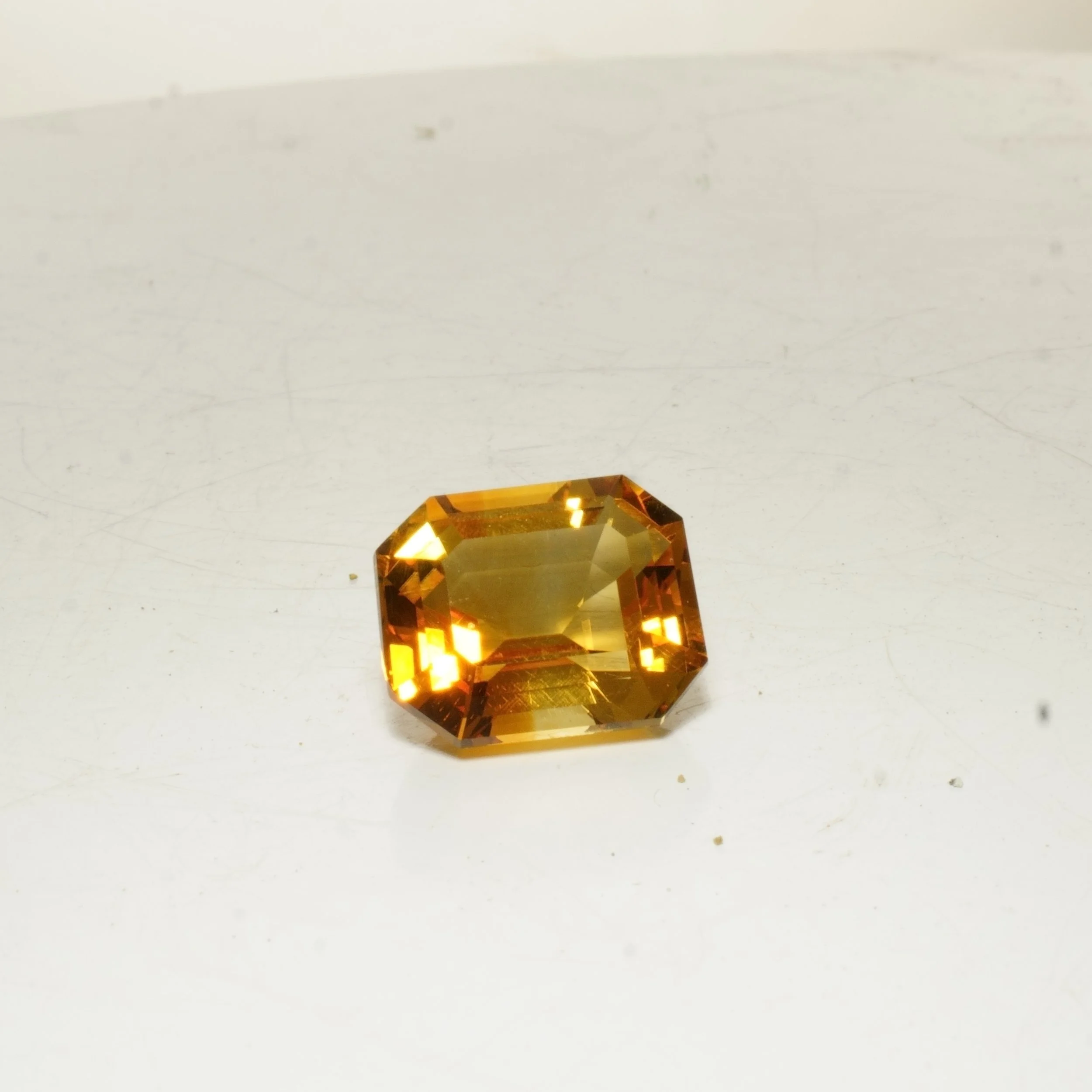 Emerald cut citrine gemstone with golden orange color, faceted rectangular cut, 8.5 carats.