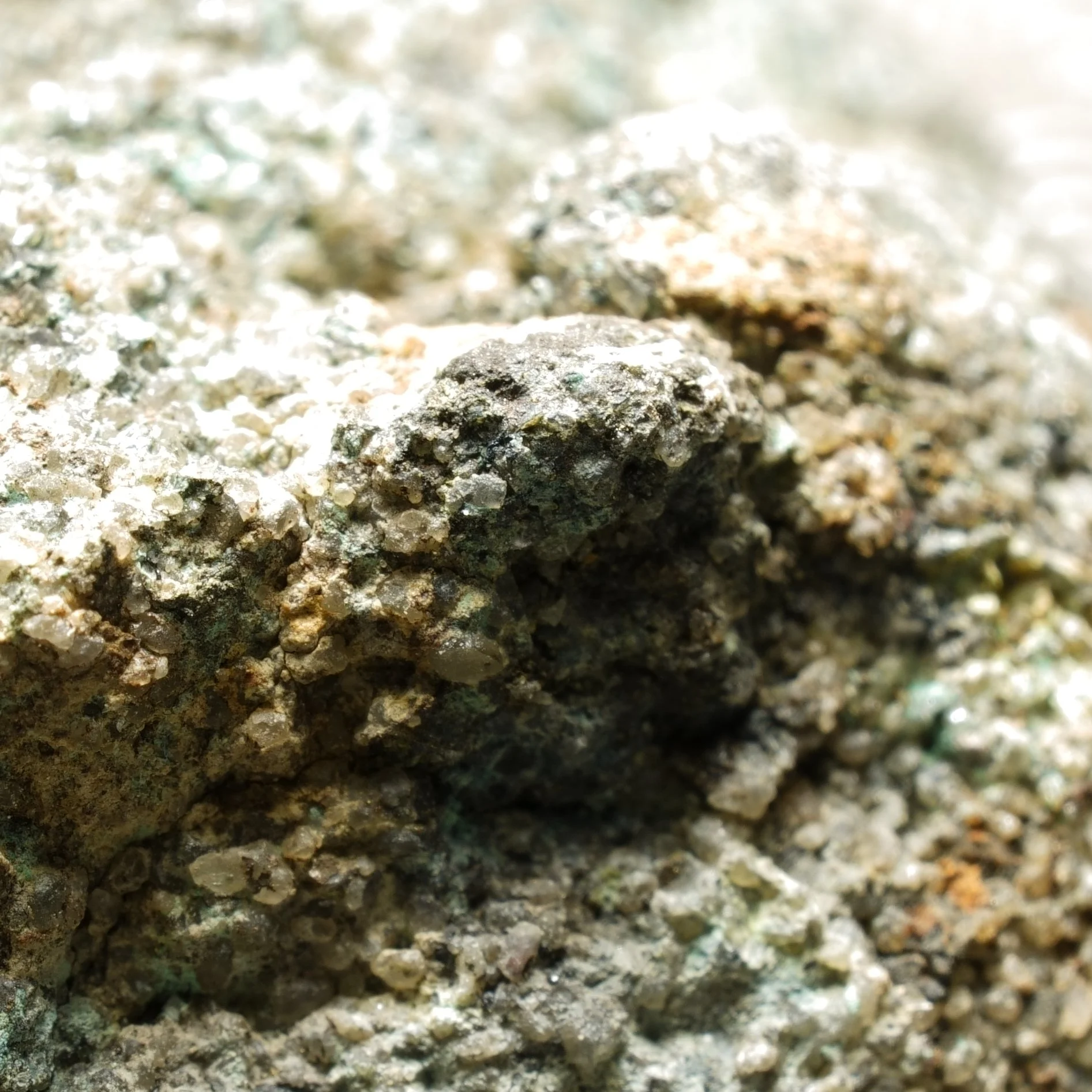 Uraninite uranium ore specimen in quartz matrix with dark primary mineralization and moderate green alteration