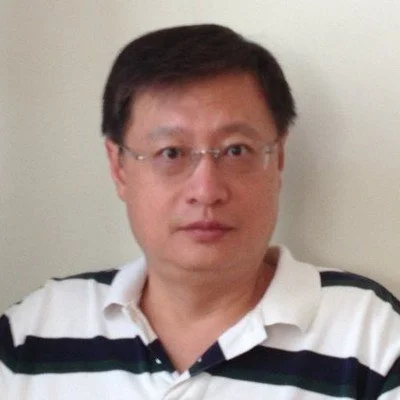 A man with glasses and short dark hair wearing a white polo shirt with black and green stripes.
