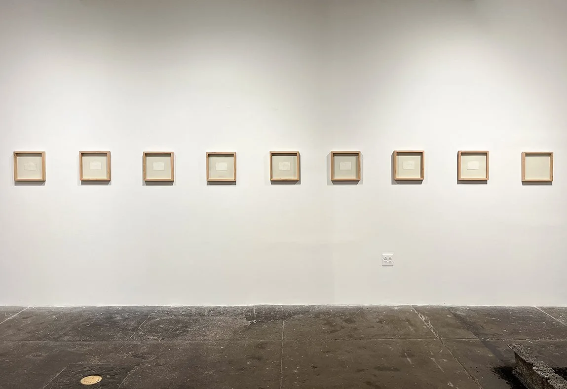 view of rear wall with row of framed paper works