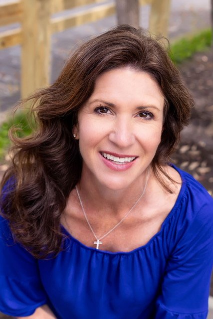 Carrie Watts with brown hair in a royal blue peasant top