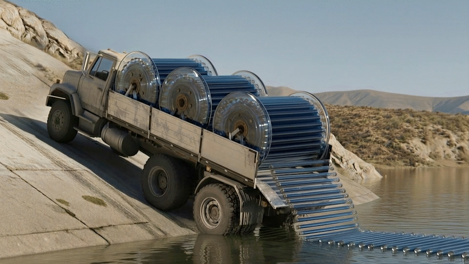 A truck unloading large blue cylindrical solar water heaters into a body of water in a desert landscape.