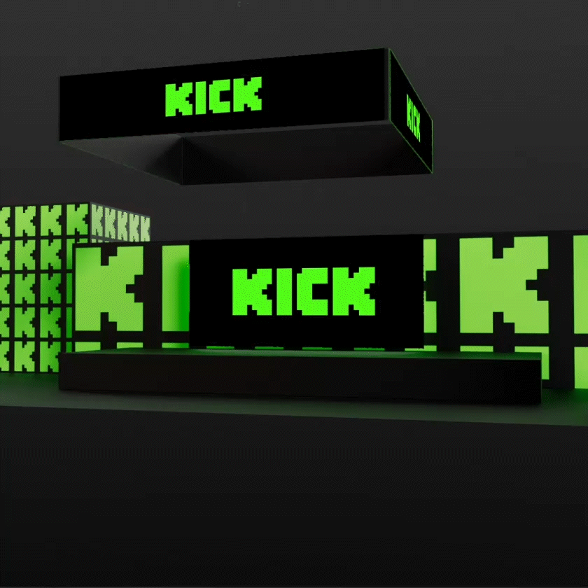 A black stage with green pixelated text screens displaying the word 'KICK' in a digital font, with a suspended black box above also displaying 'KICK' in green.