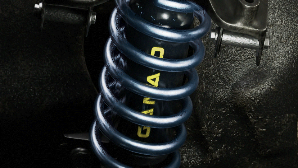 Close-up of a vehicle suspension coil spring in blue, with a shock absorber behind it labeled 'GAS' in yellow, on a textured black surface.