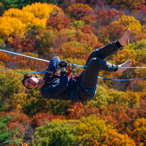 Image of Instructor, Kayla Kroot, hanging from knees and elbows on a highline.