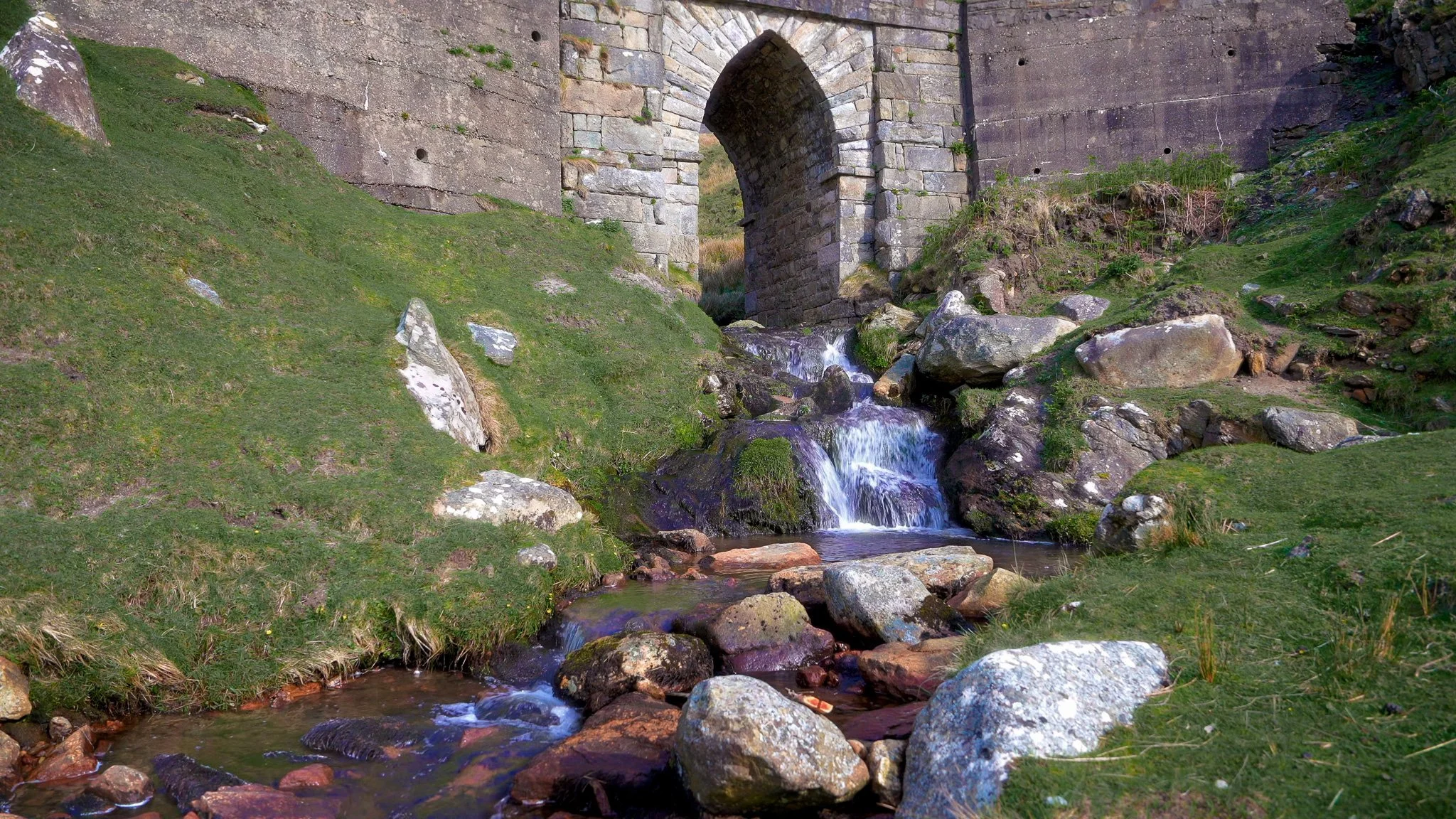 Irish stream flowing beneath an old stone arch in Ireland, featured in Whispers Beneath the Stone Arch, a 3-hour calming piano video by Dean Best.