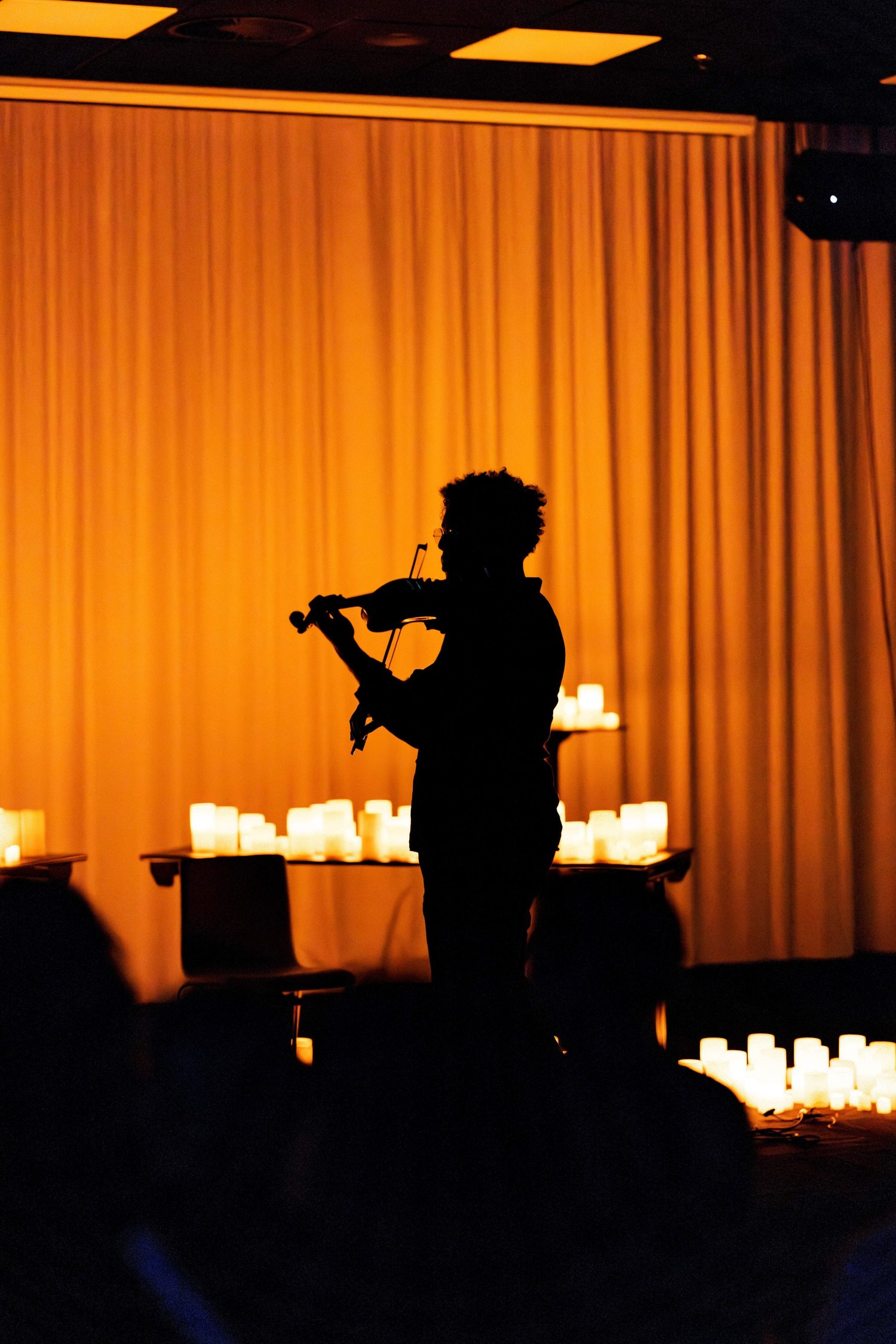 Violinist playing among thousands of candles