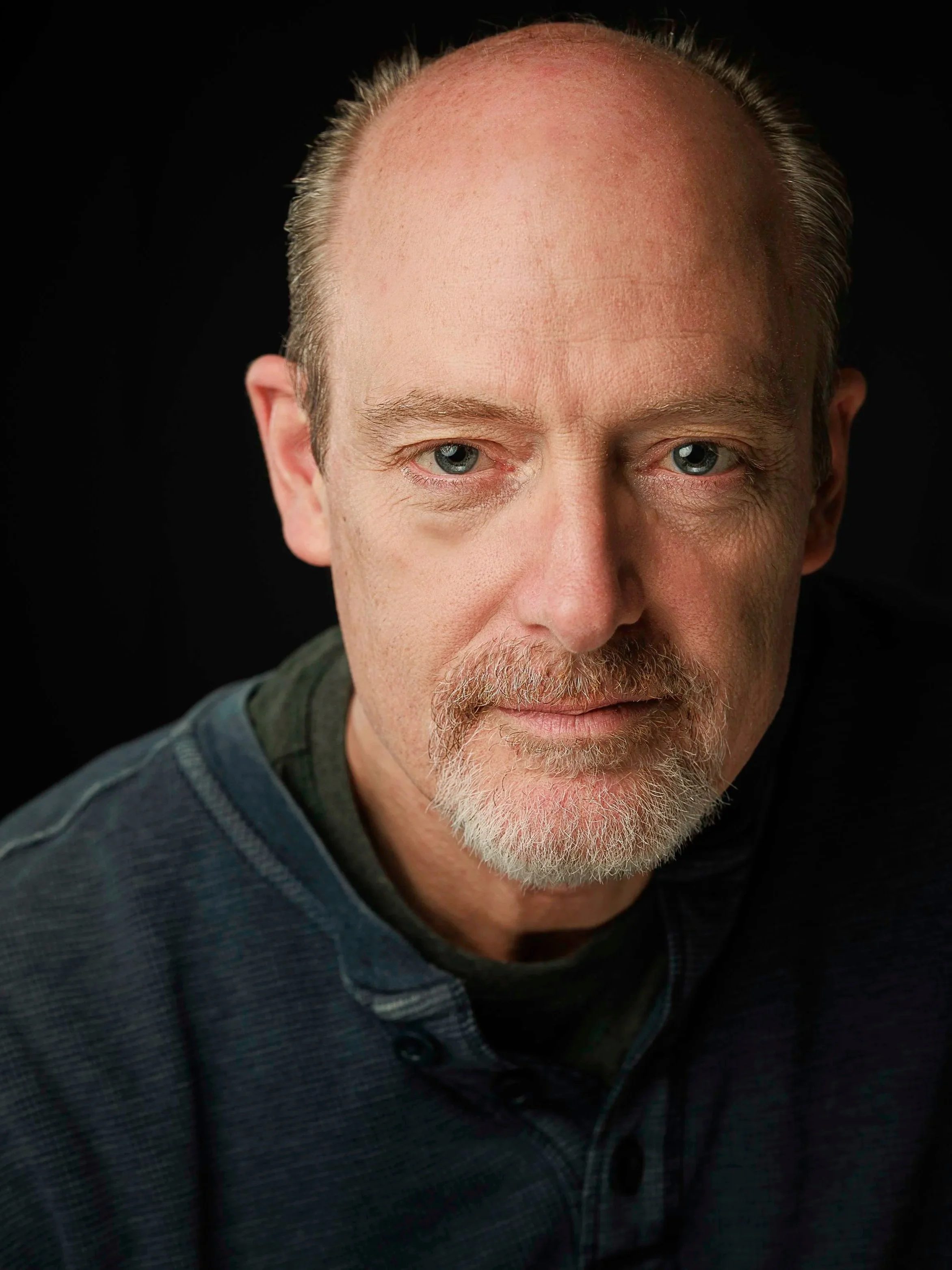Studio headshot of a man against a dark background, photographed in Paris