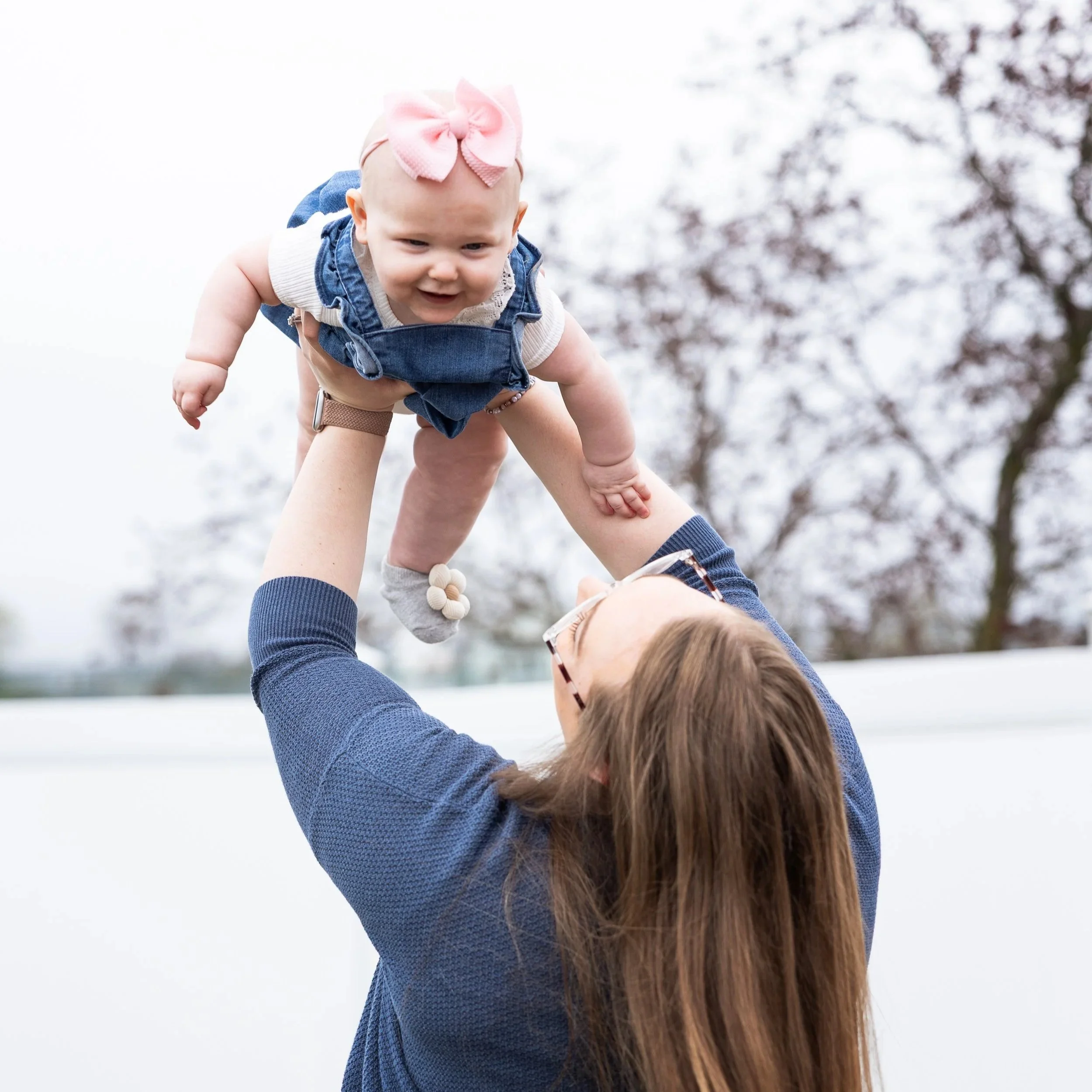 Mother lifting her baby in the air during a joyful family portrait session