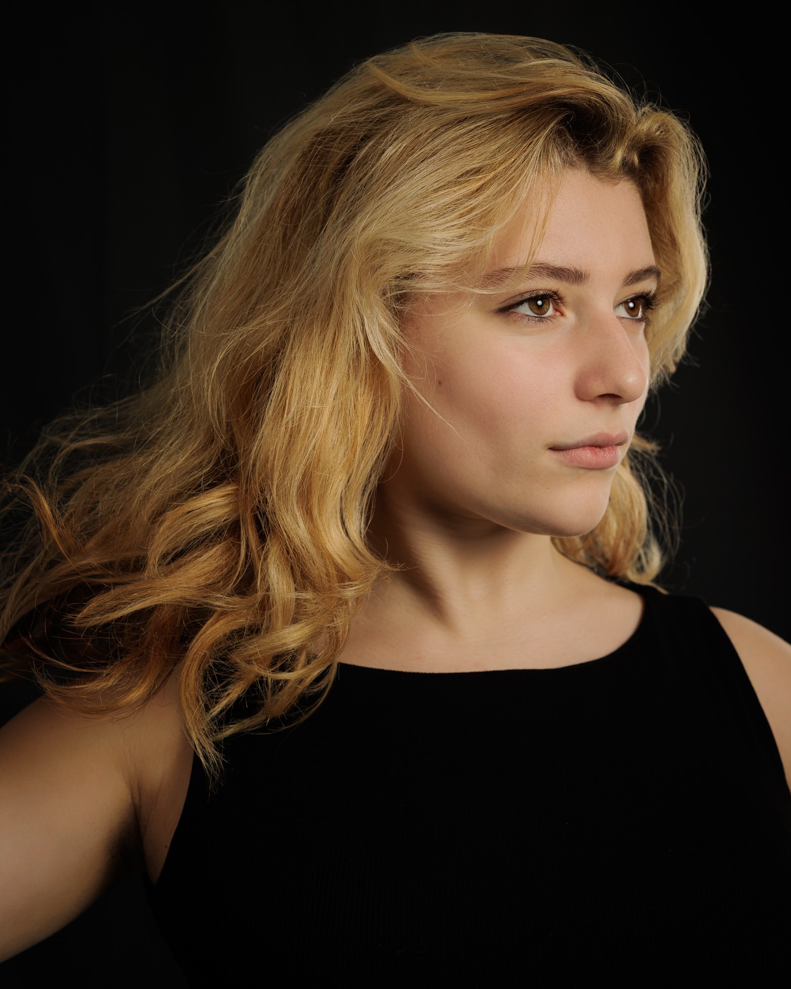 Studio portrait of actress Hannah Castel-Chiche in profile against a dark background