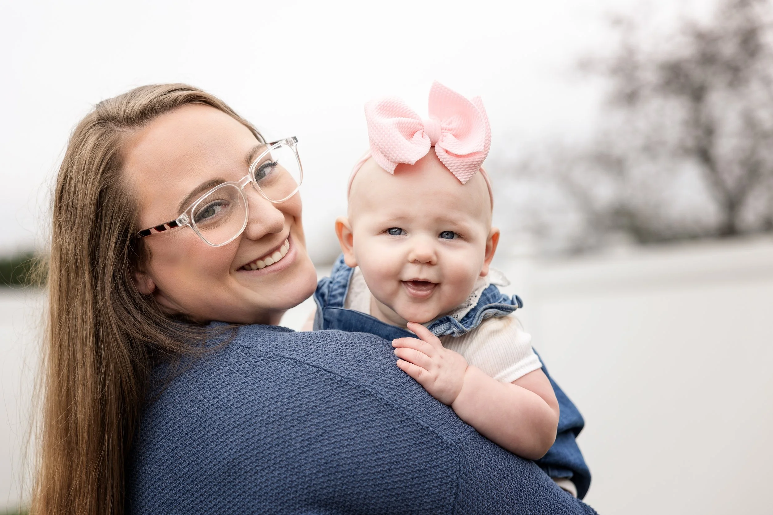 Mother holding smiling baby girl during an outdoor family photography session