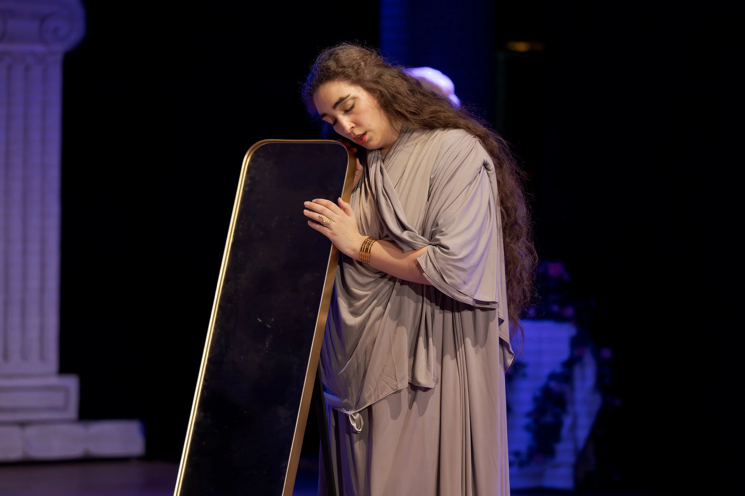 Clara Zammit as Hélène leans against a mirror during a quiet moment in La Belle Hélène.