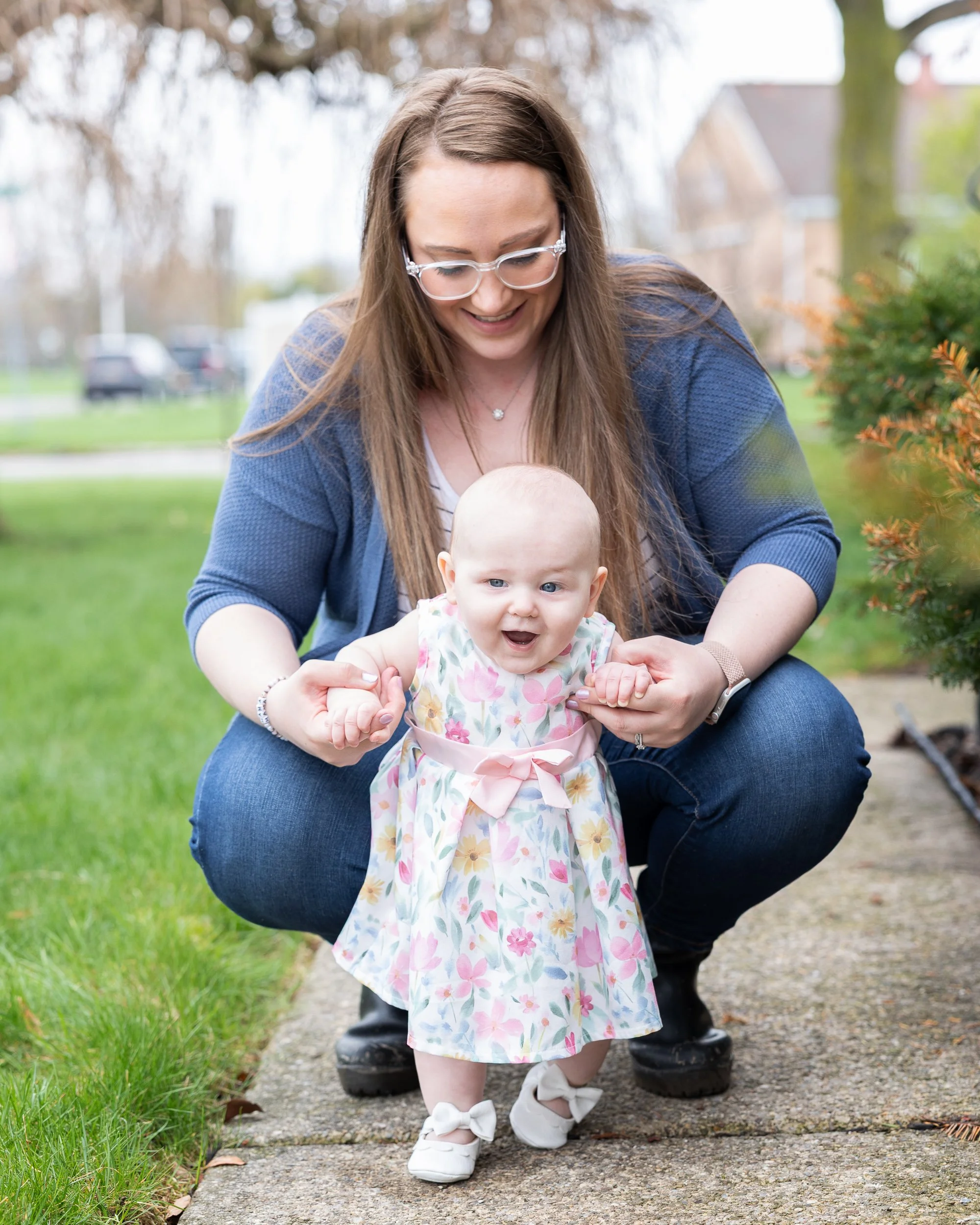 Mother holding her seven-month-old daughter outdoors during a relaxed family photography session.