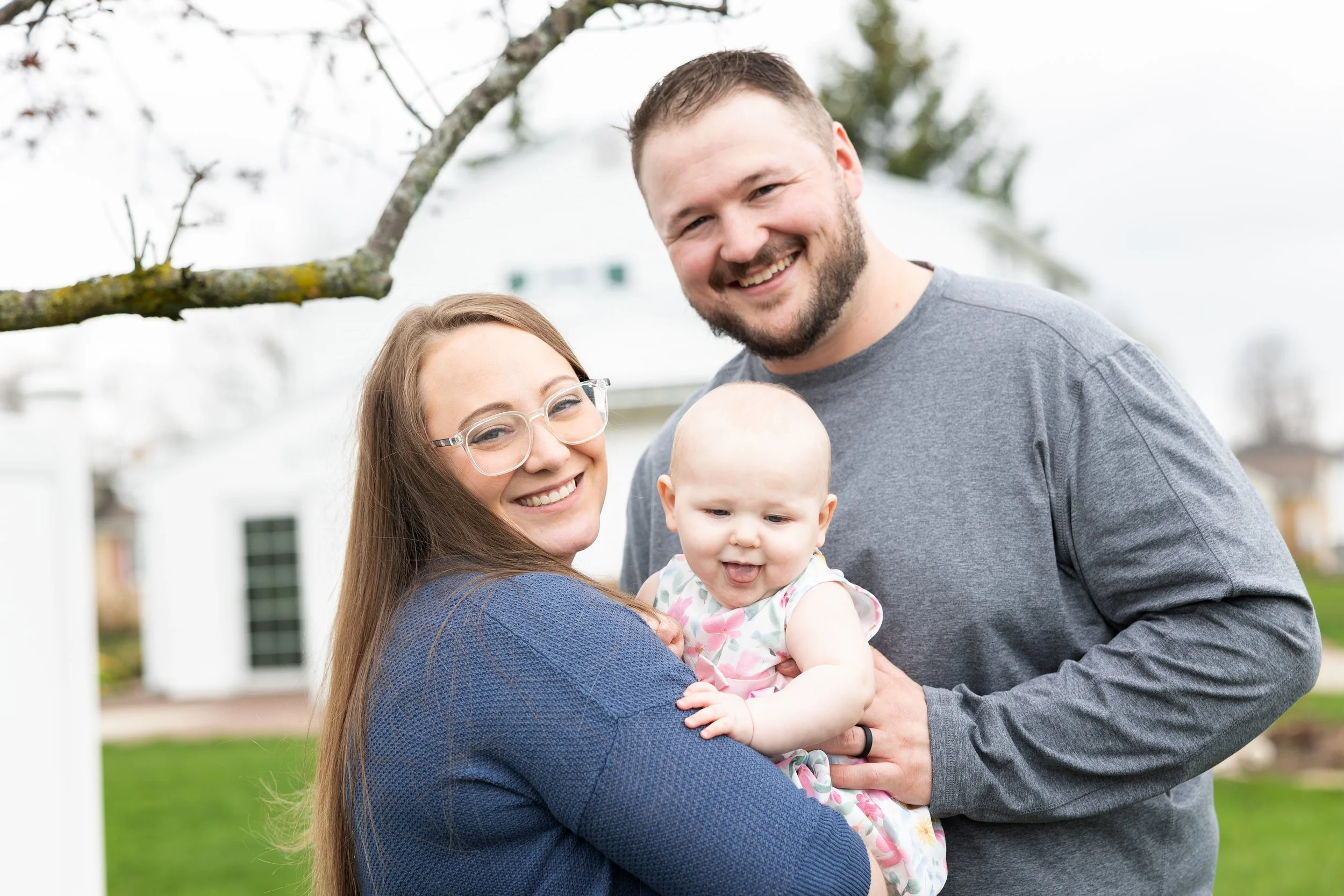 Outdoor family portrait of parents holding smiling baby girl during lifestyle photography session