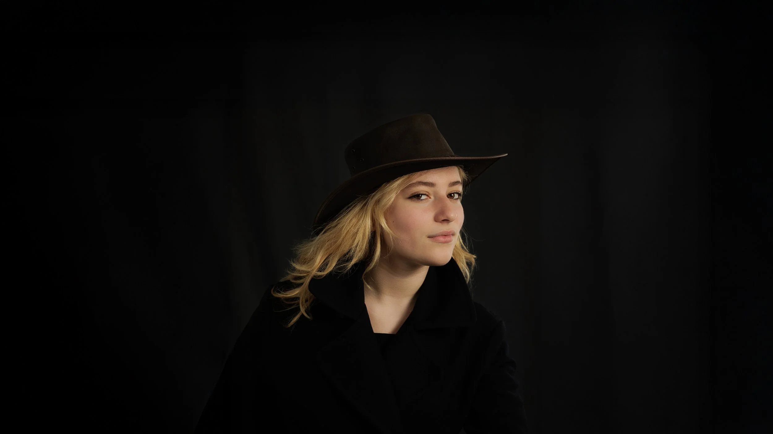 Studio portrait of a young actress with soft directional lighting and a calm, expressive gaze, photographed in Paris by Caroline Coyner.