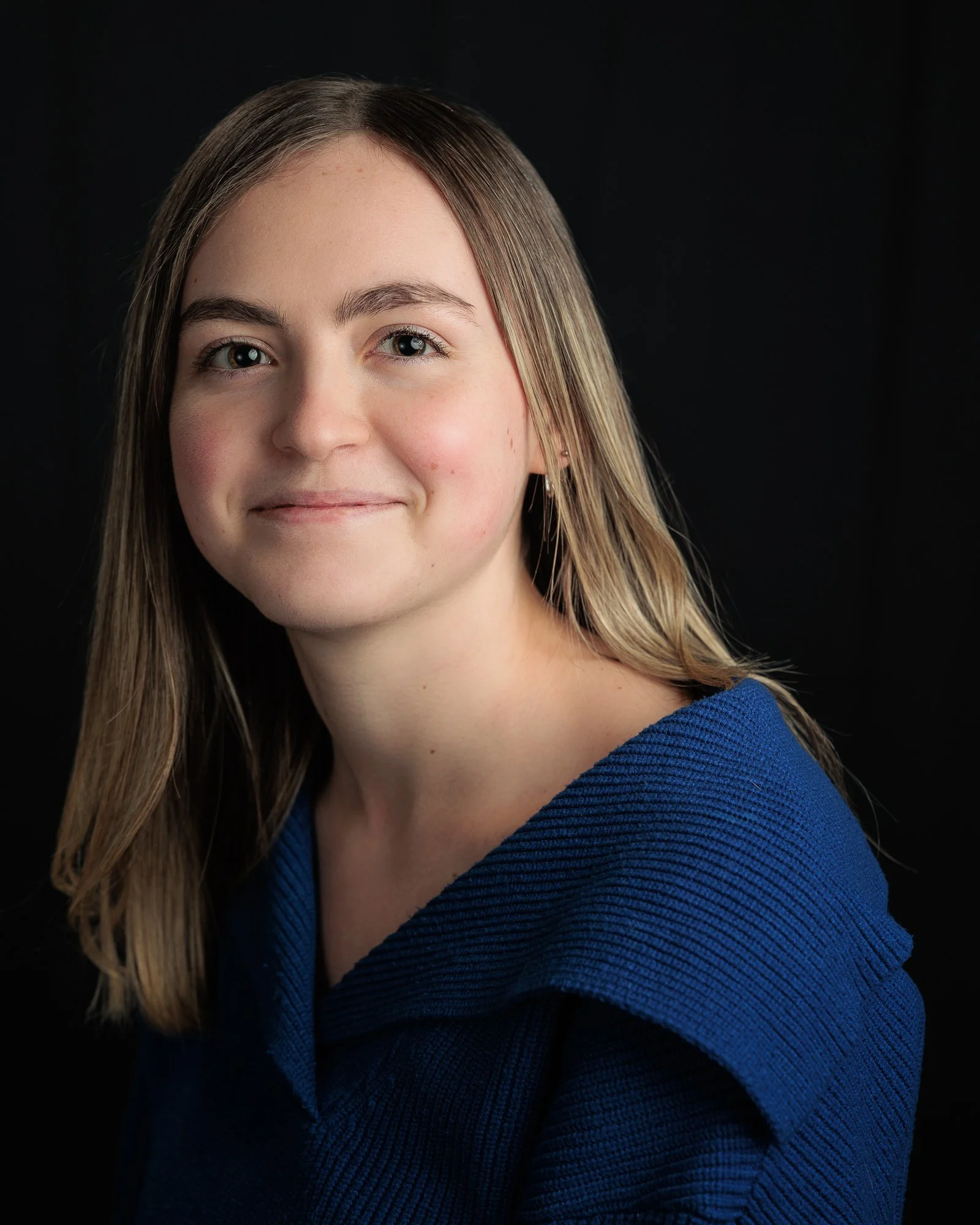 Natural portrait of a young woman with soft lighting against a dark background, photographed in Paris by Caroline Coyner.