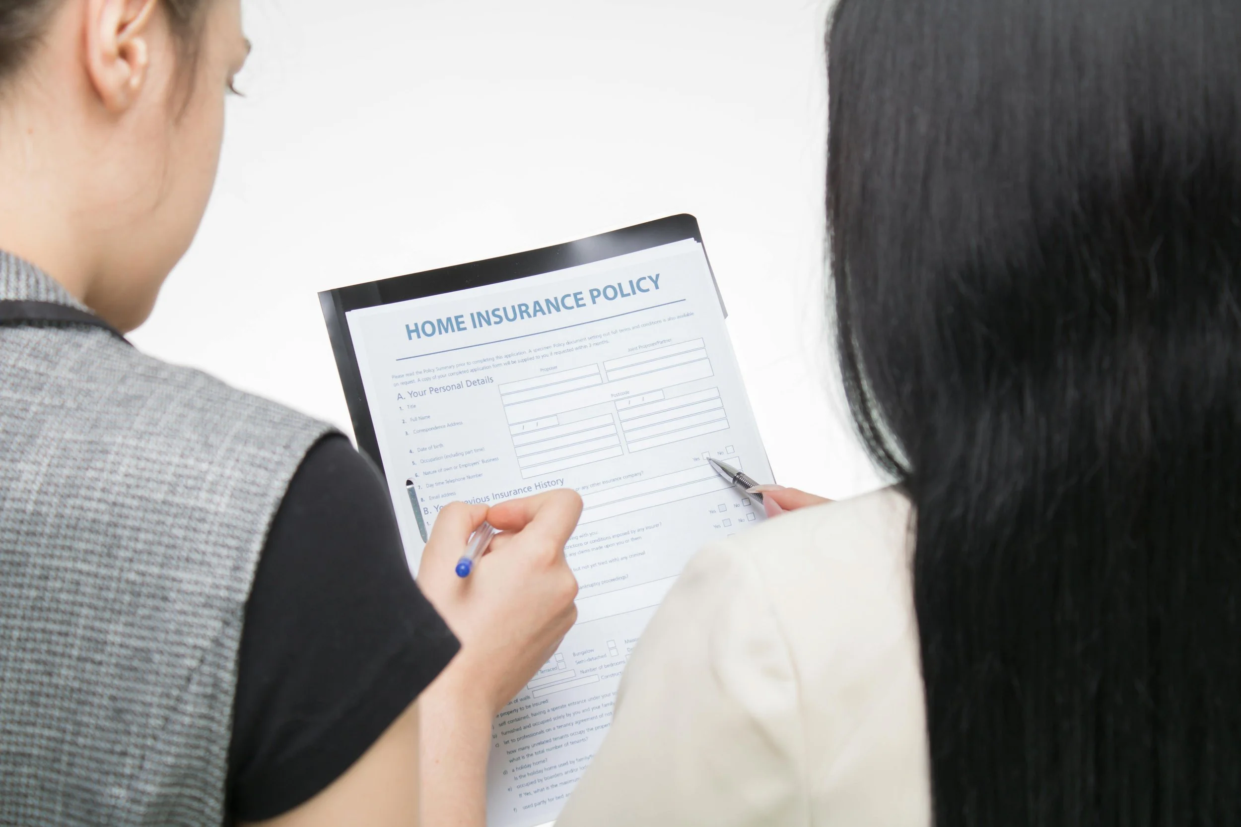 Two women reviewing a home insurance policy form together.
