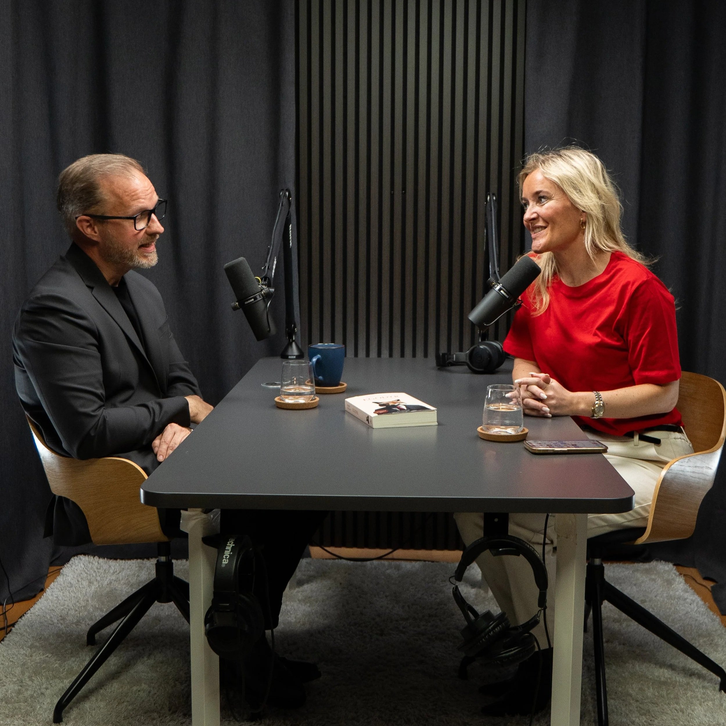 Podcast vært optager i podcast studie med fokus på samtale og indhold fremfor teknik og udstyr.