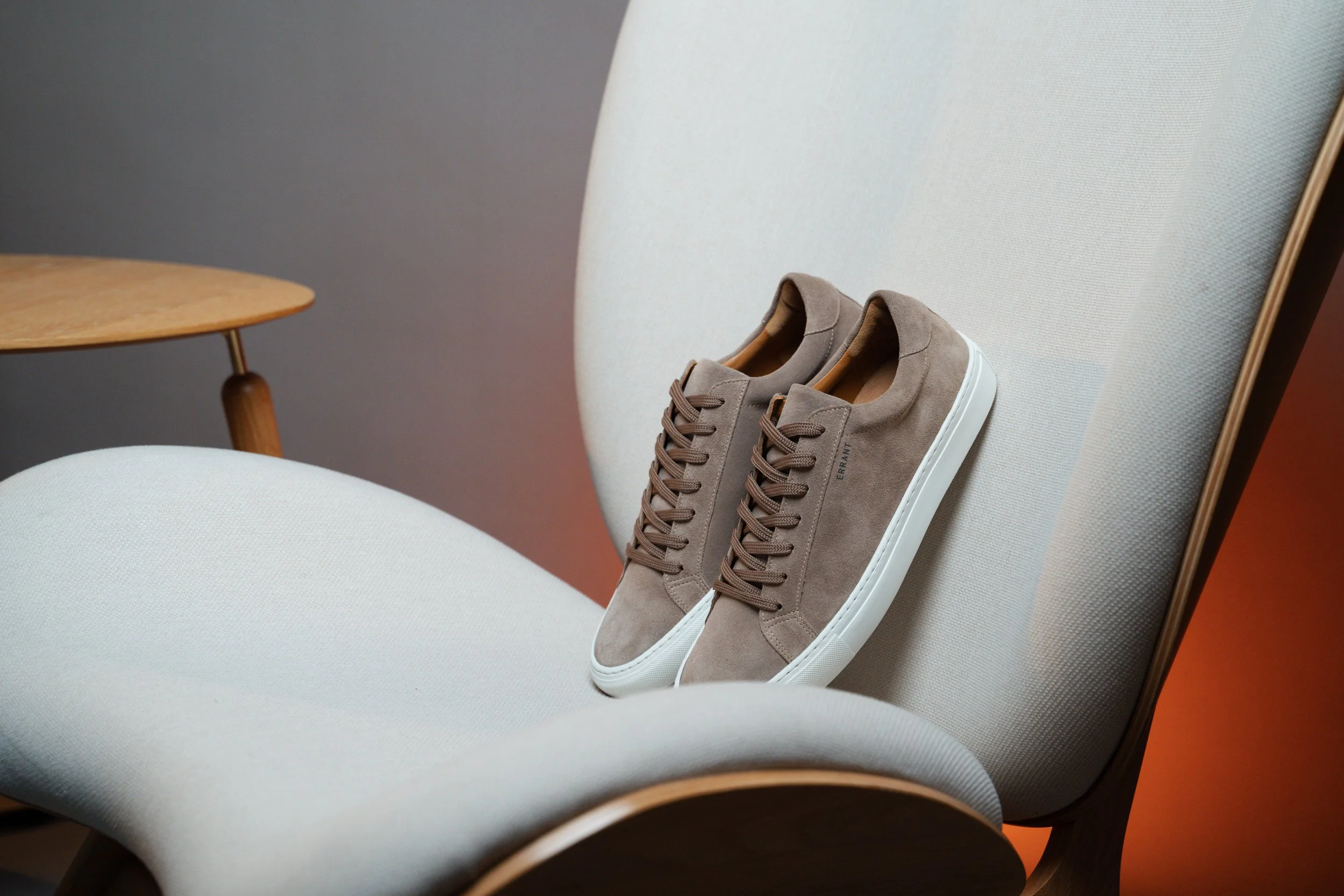 Brune sneakers på en lysegrå stol.
