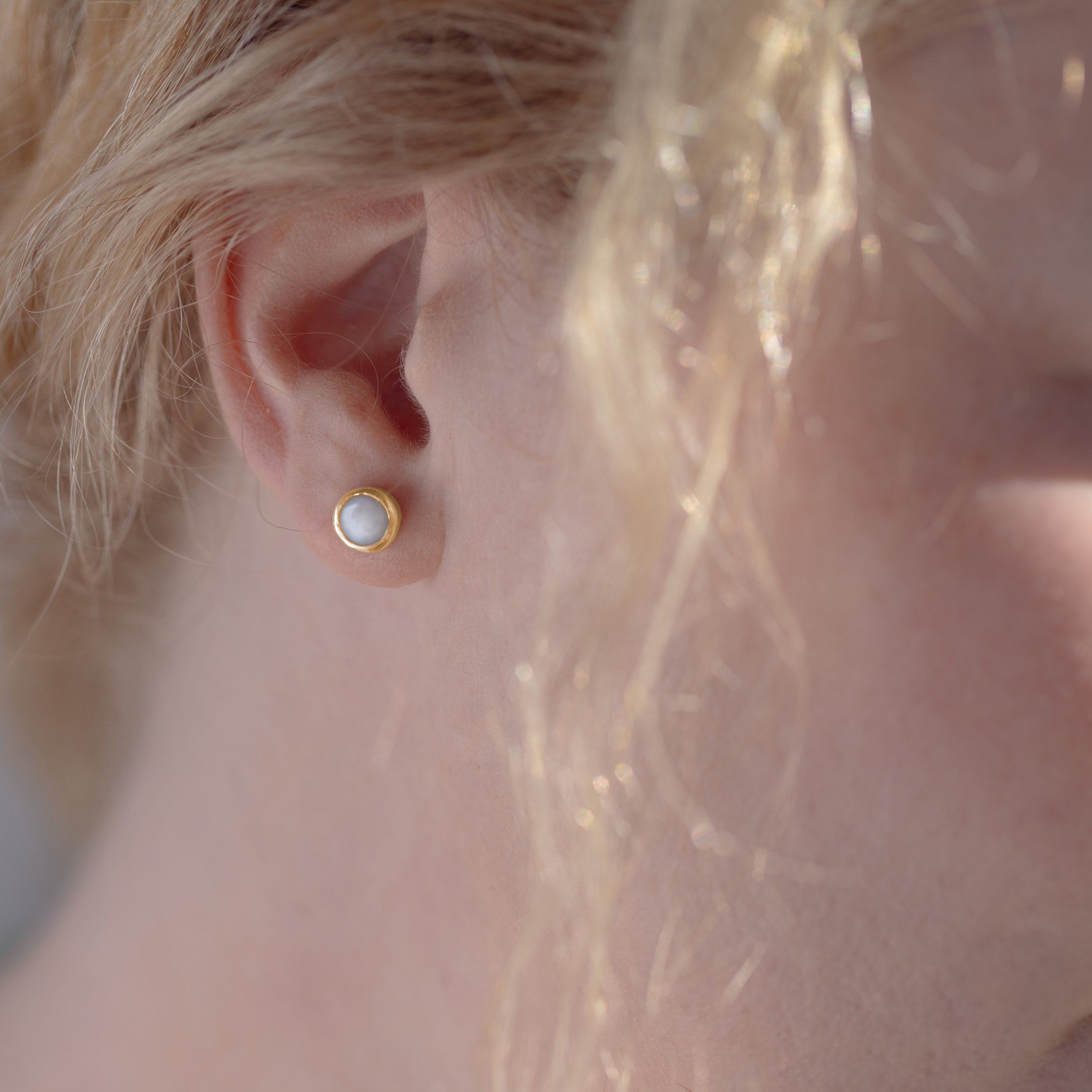 Gold breastmilk stud earrings on ear.jpg