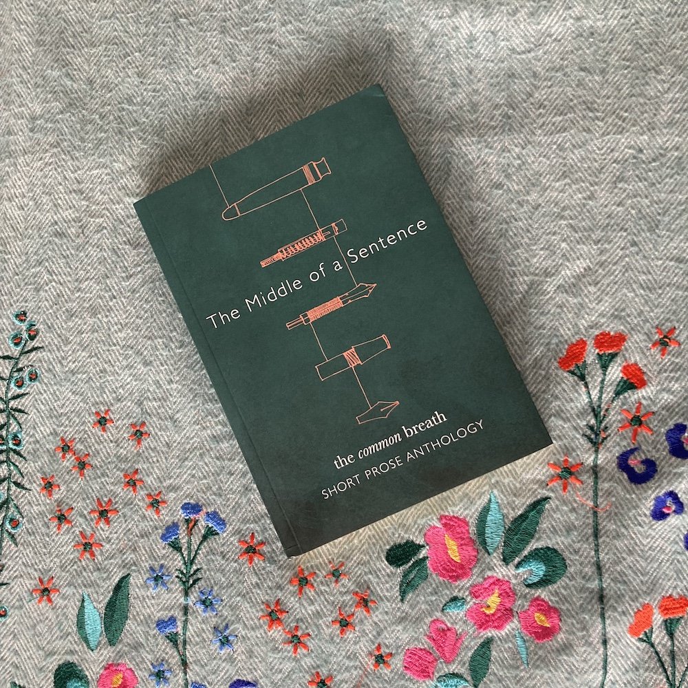 A dark green book 'The Middle of Sentence' lying on a floral embroidered blanket