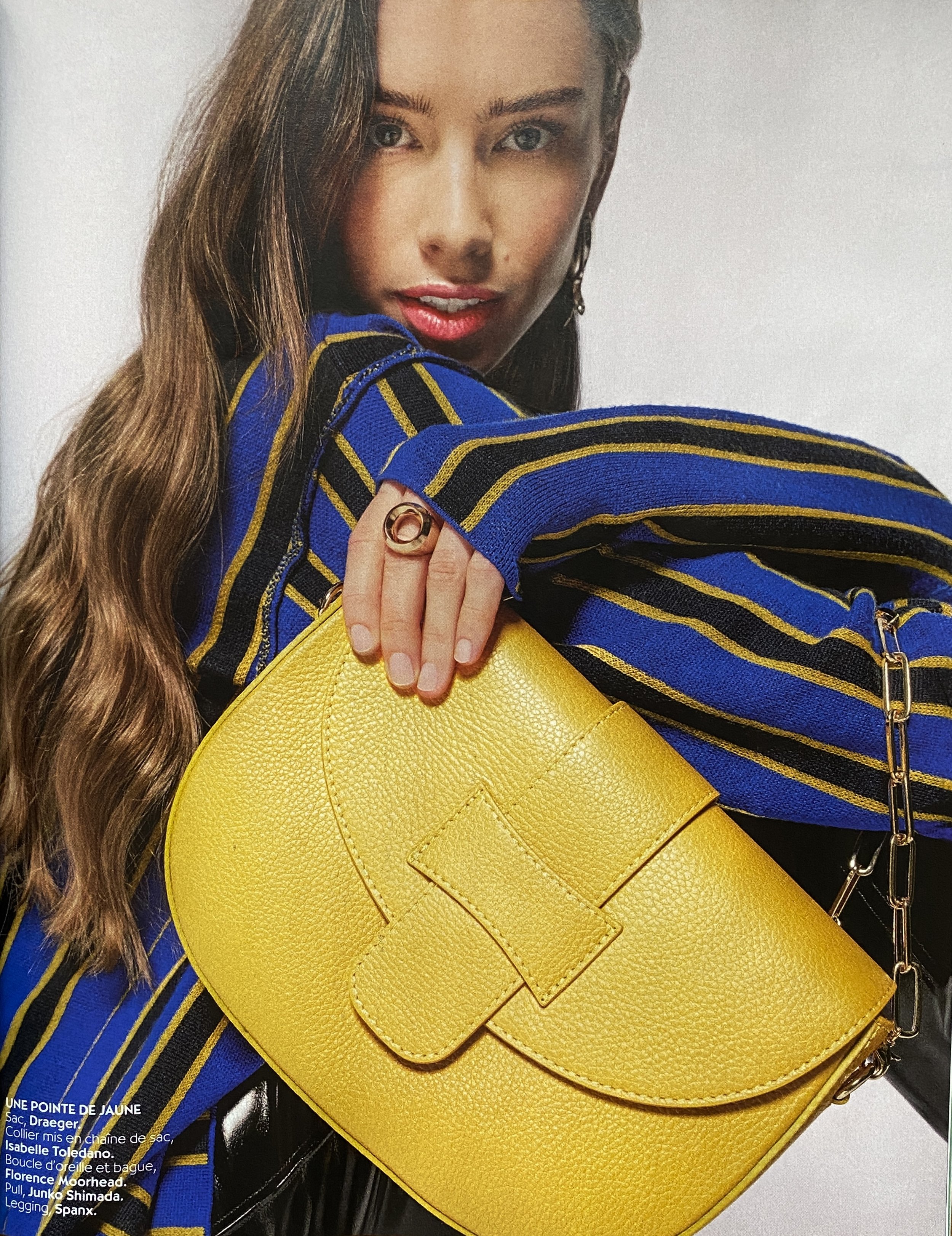 Une femme pose avec un sac jaune en cuir et une bague dorée
