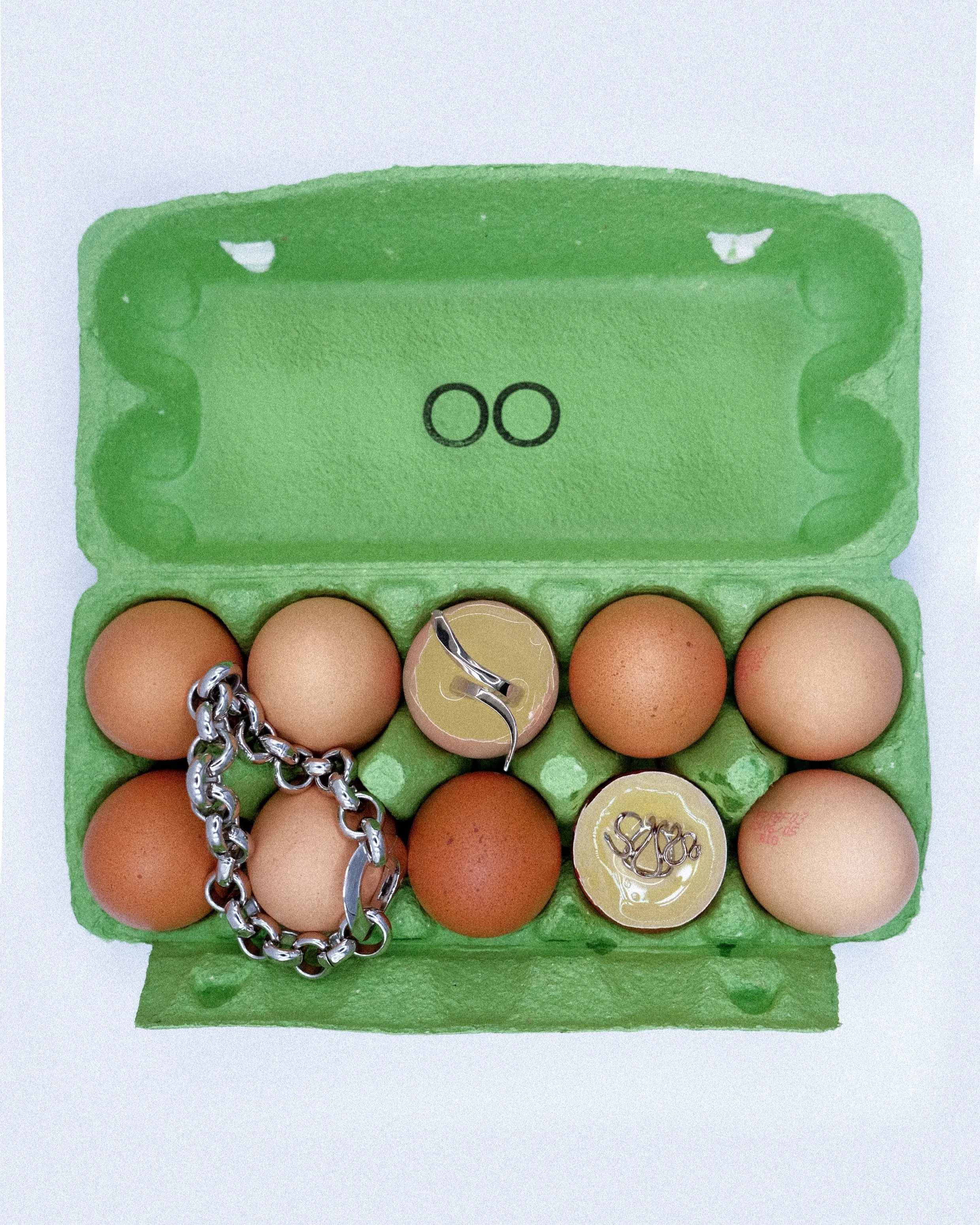 Une boîte à œufs contenant huit œufs, un collier, une bague et un bijou d'oreille argentés