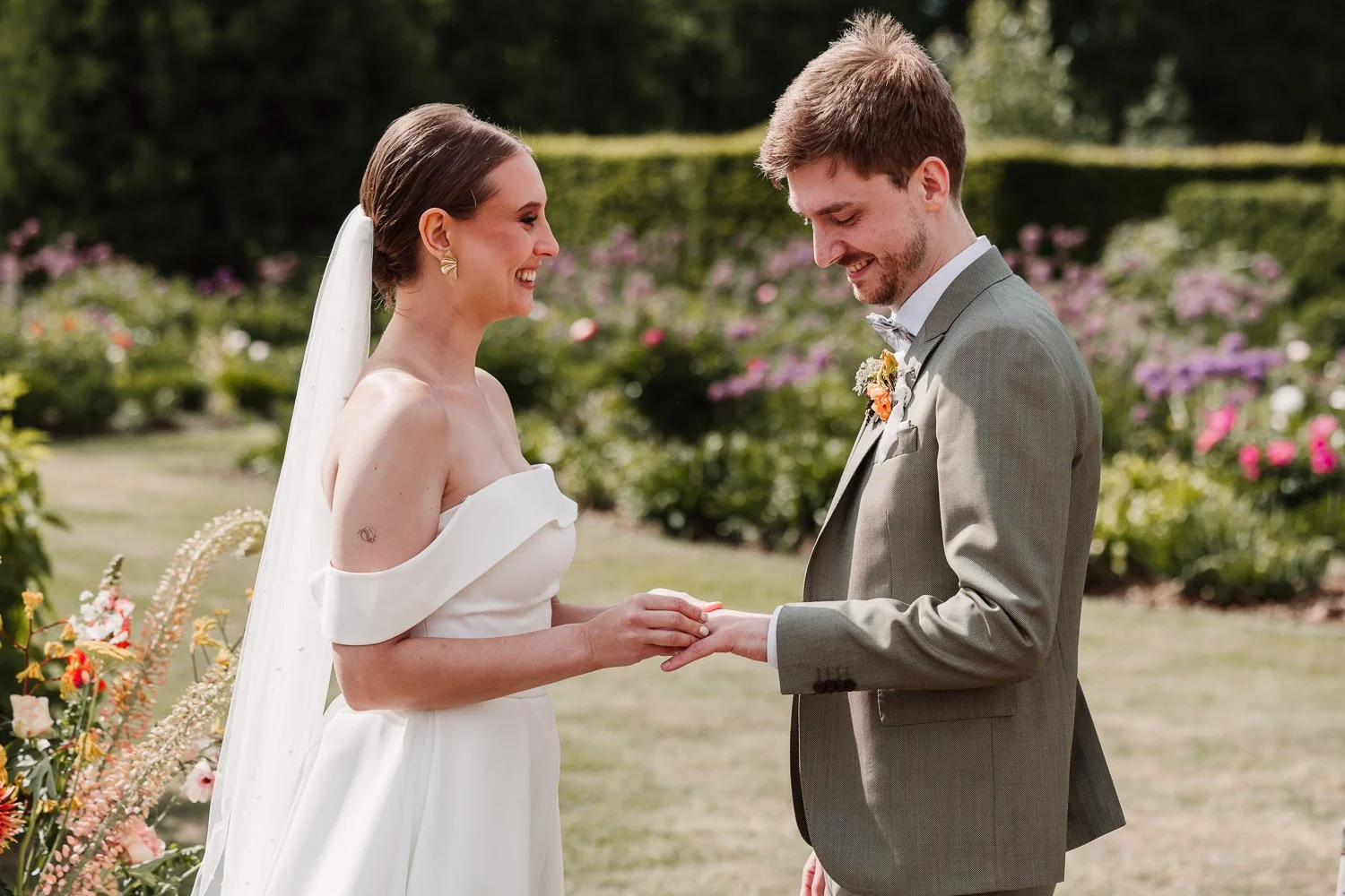 Koppeltje krijgt trouwgeloften uit in een tuin met veel bloemen.