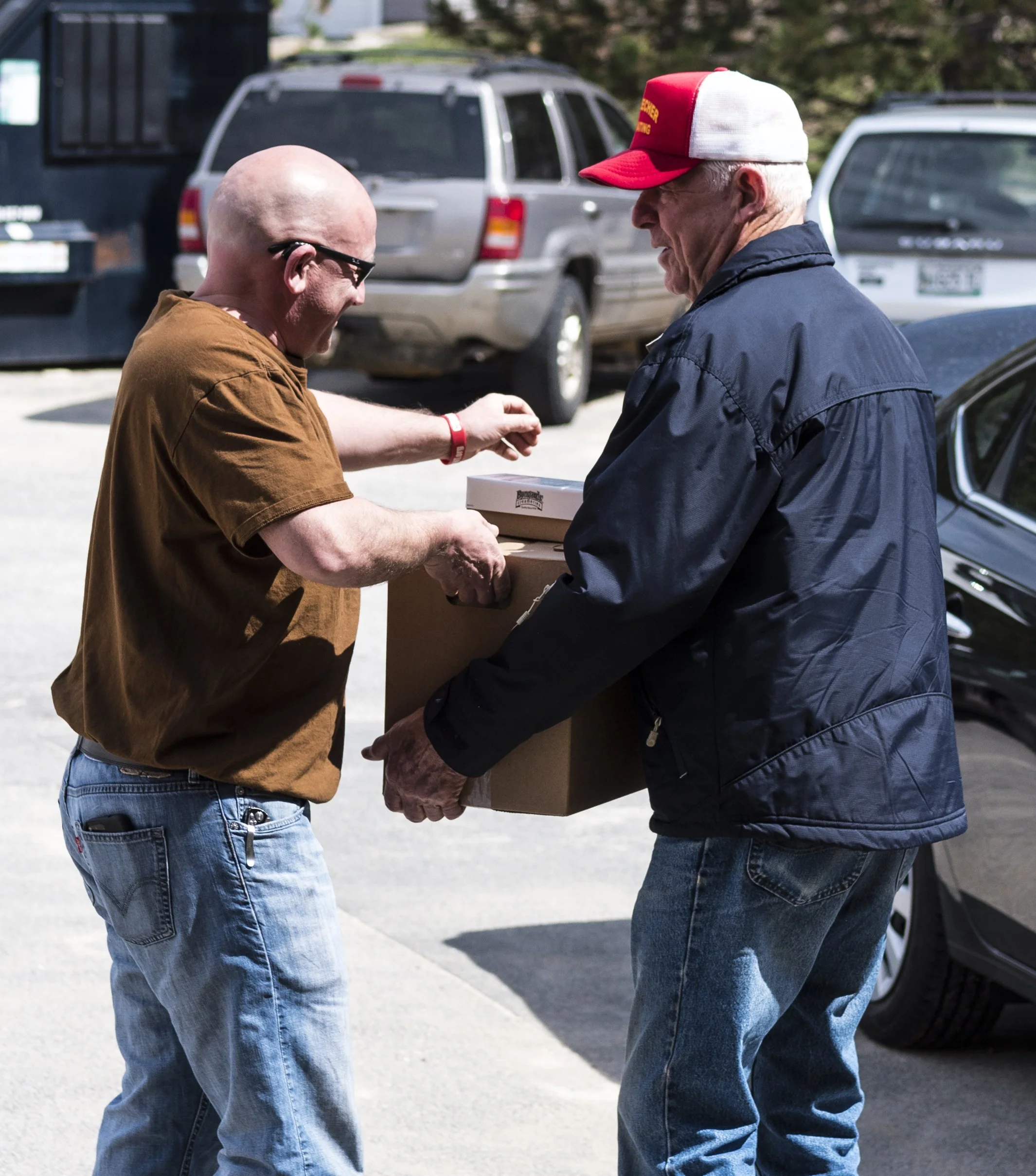 One man handing a box to another man