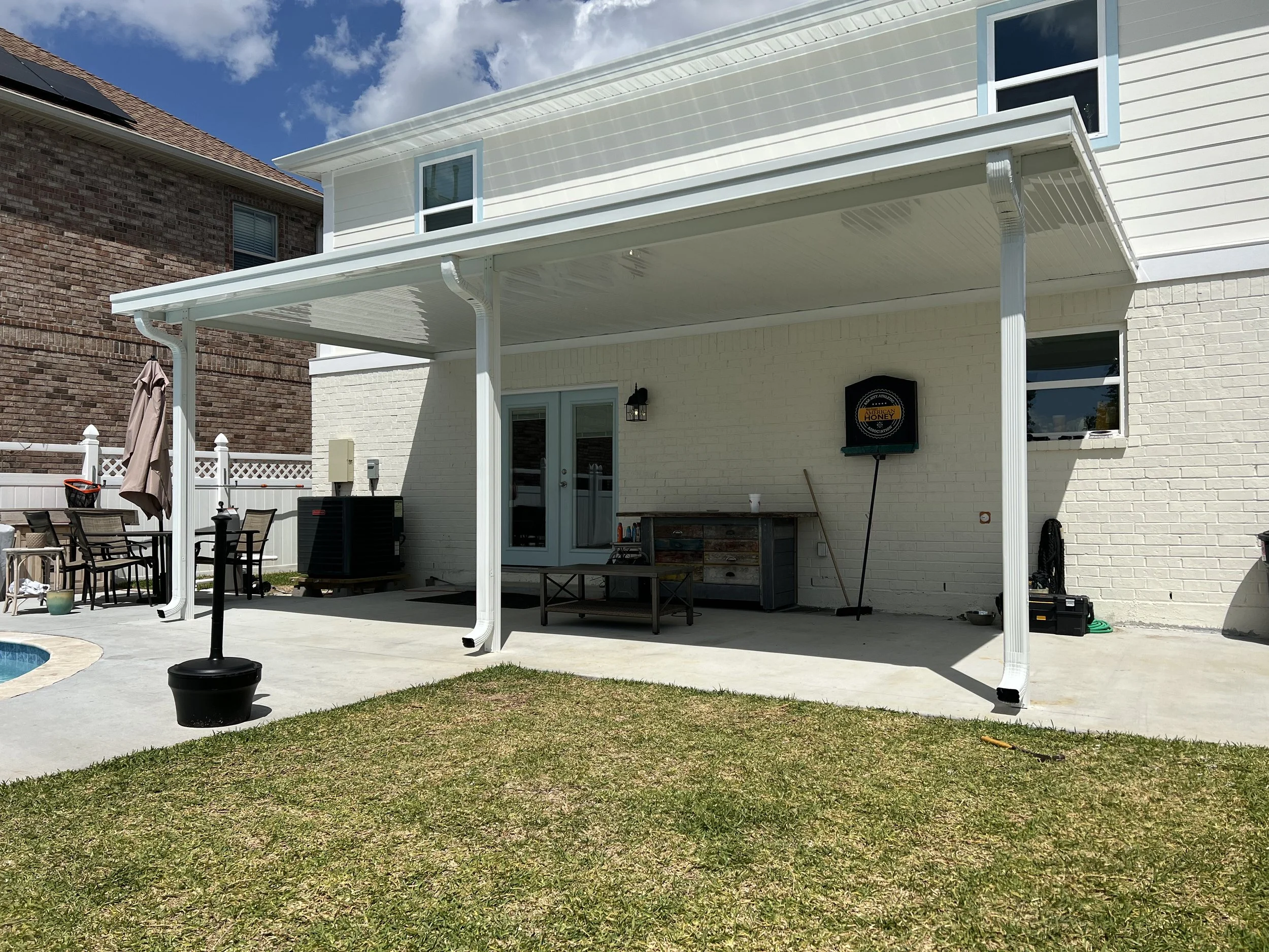 Backyard patio with a covered seating area, outdoor furniture, and grassy lawn