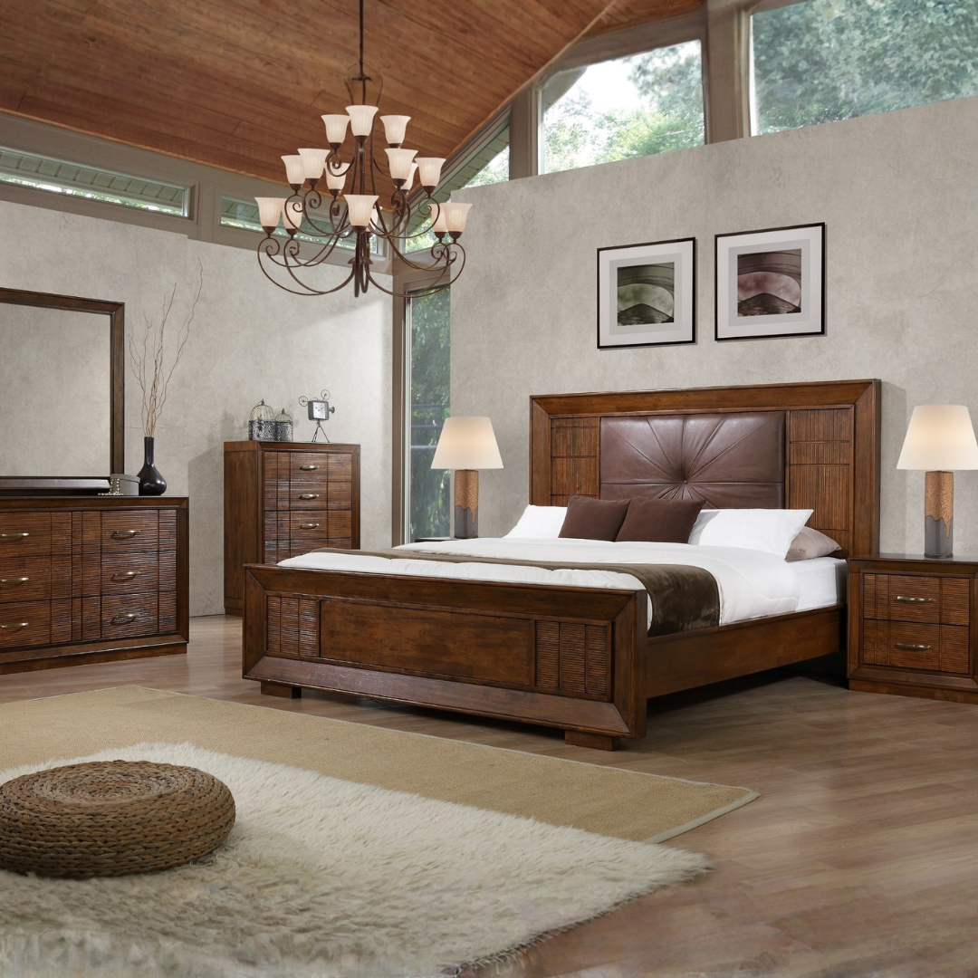 Een slaapkamer met een groot houten bed, twee nachtkasten met lampen, een houten dressoir, een grote spiegel, een moderne pendellamp en twee kunstwerken boven het bed. De kamer heeft een houten plafond en grote ramen met uitzicht op groen.