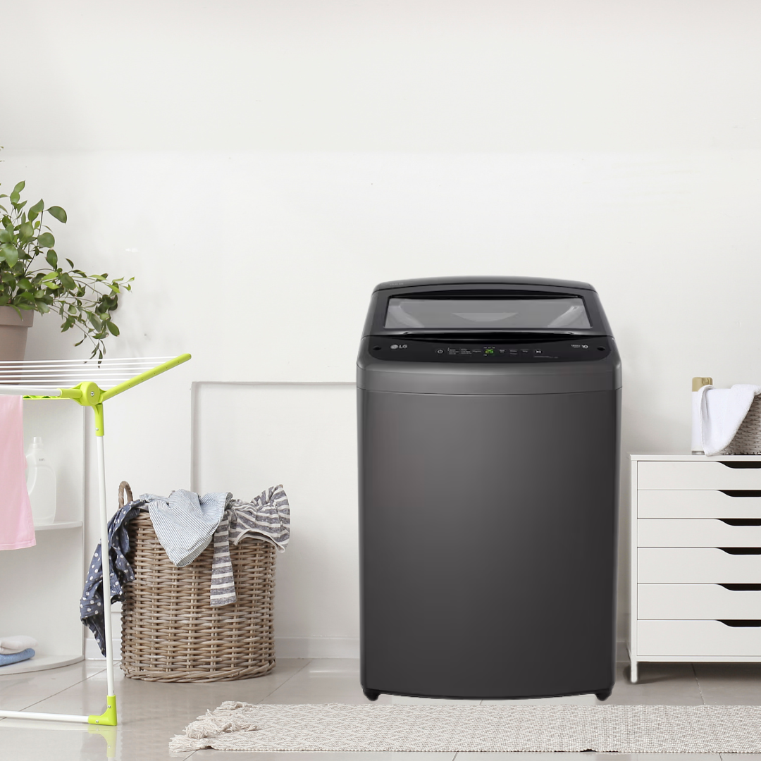 Wasmachine in een wasruimte met mand, wasgoed, kast en planten.