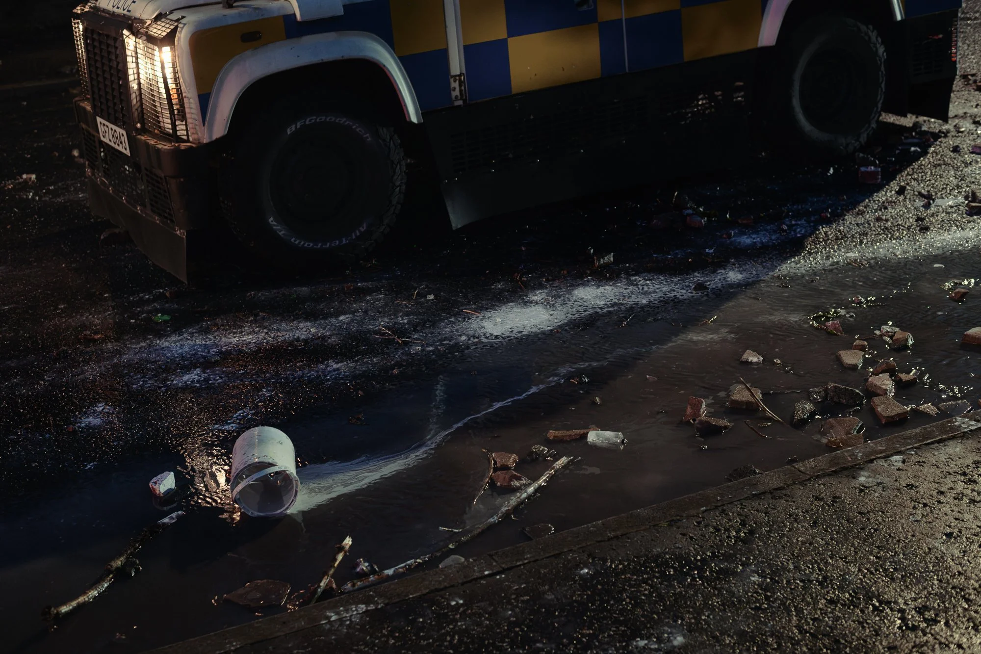 Projectiles in runoff from police water cannon remain on the street after clashes. Belfast. 2026